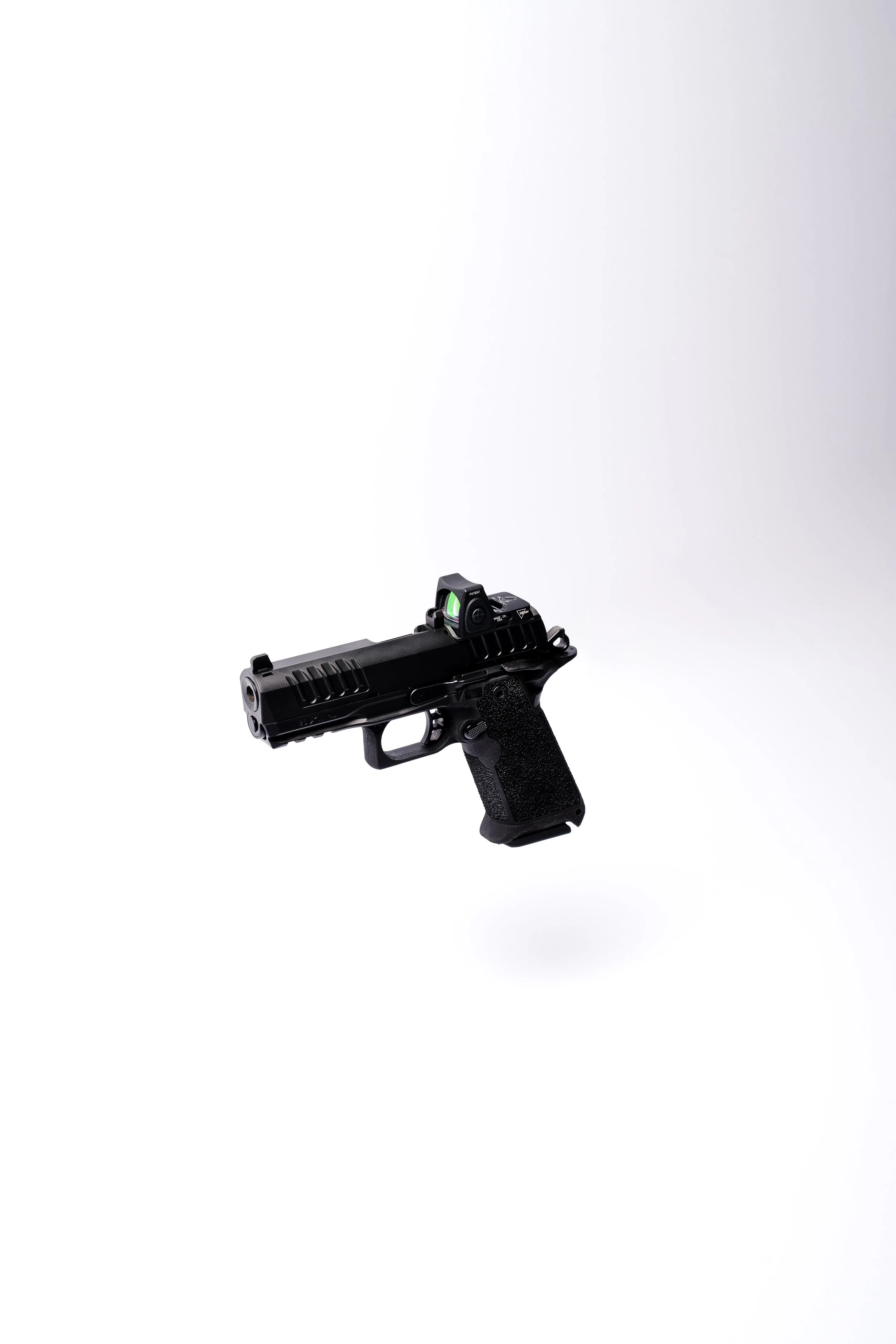 A black handgun with a mounted red dot sight, floating against a plain white background.
