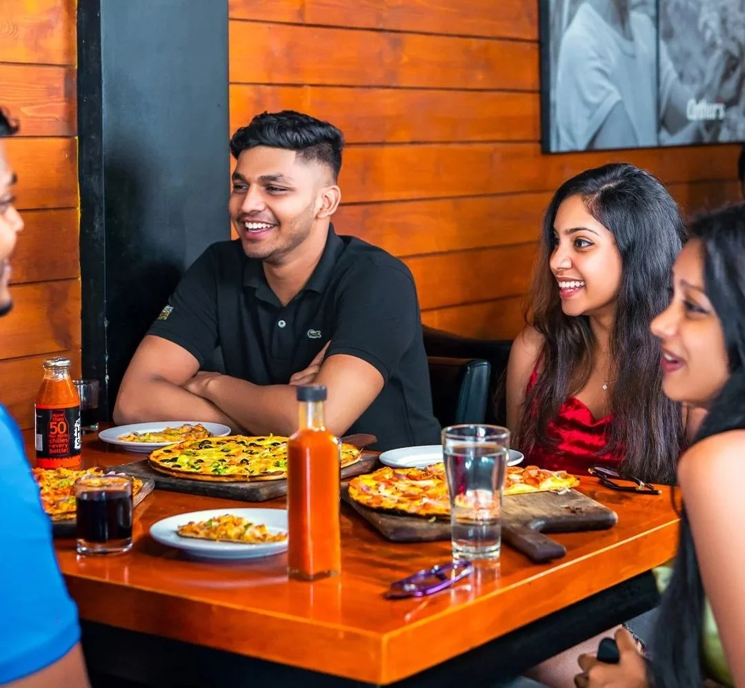 A group of friends enjoying pizza and drinks at a restaurant.