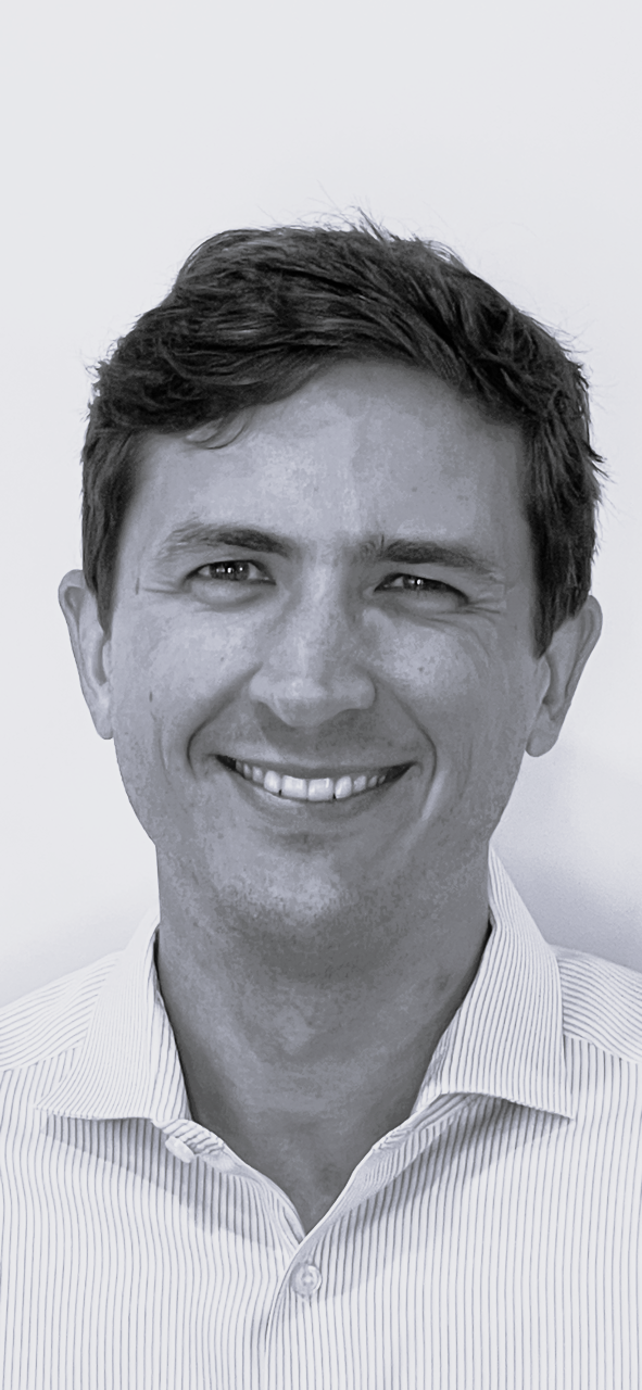 Black and white portrait of a smiling man with short, dark hair, wearing a striped collared shirt.