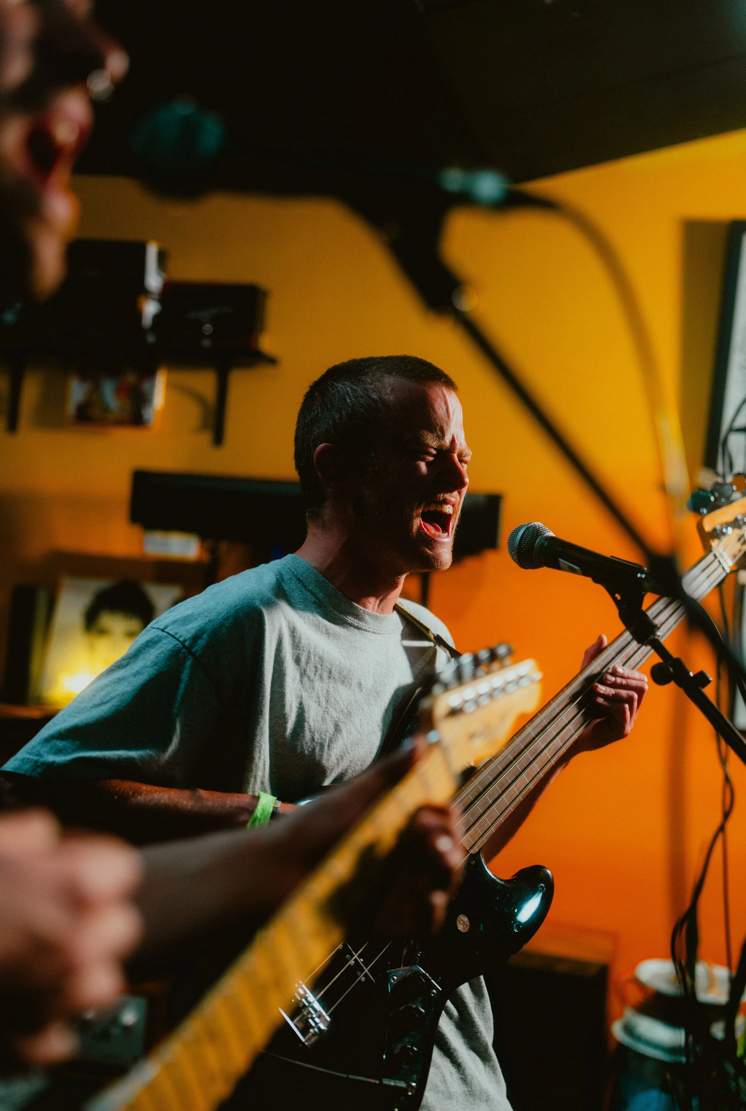 A man singing passionately into a microphone while playing an electric guitar in a dimly lit room.