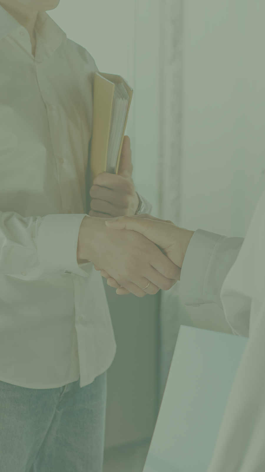 Two people shaking hands in a professional setting, one holding a notebook.