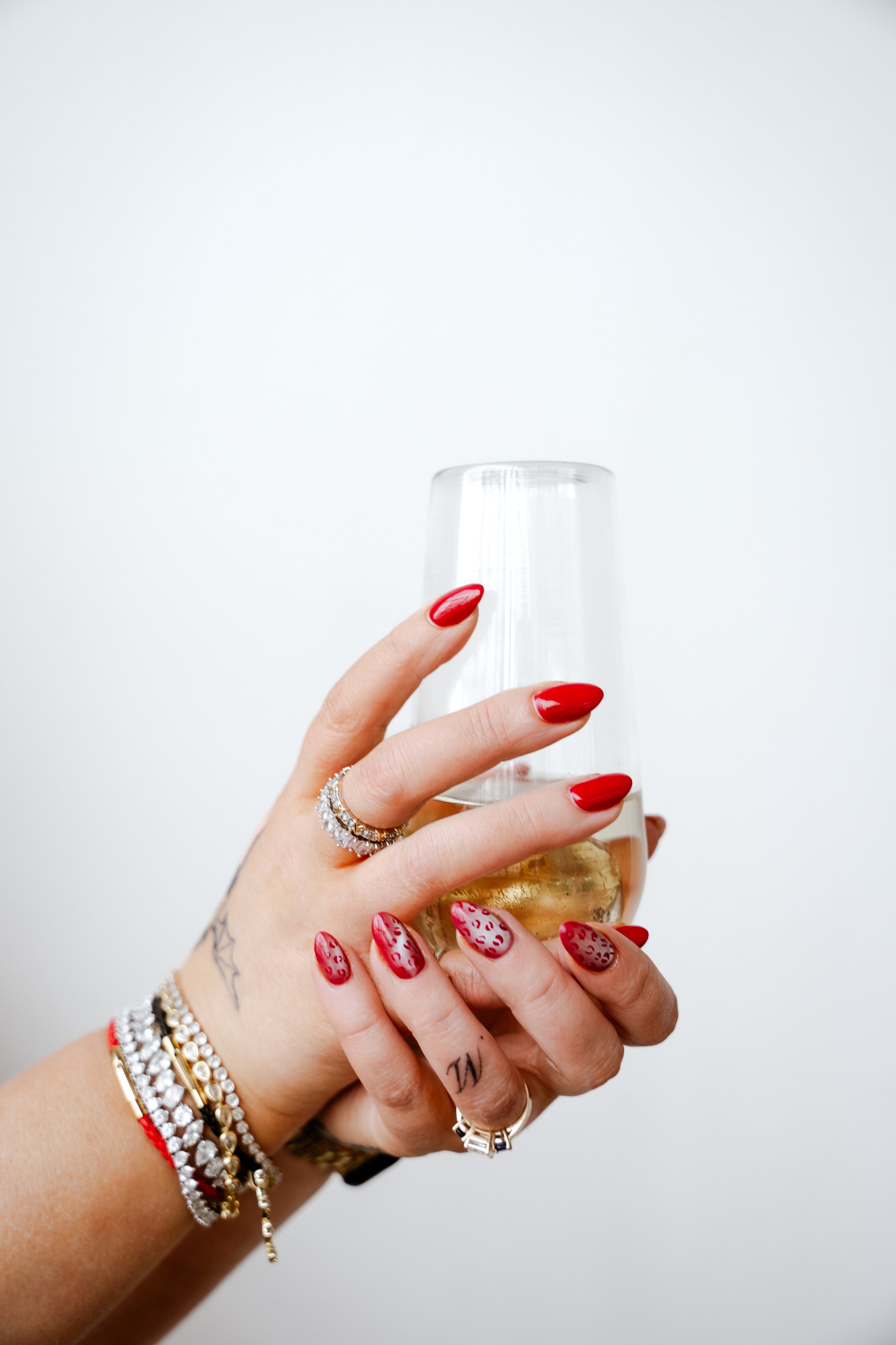 Glossy red manicure with gold jewelry by Salon 2 You luxury nail salon serving Lakewood and Cleveland Ohio.