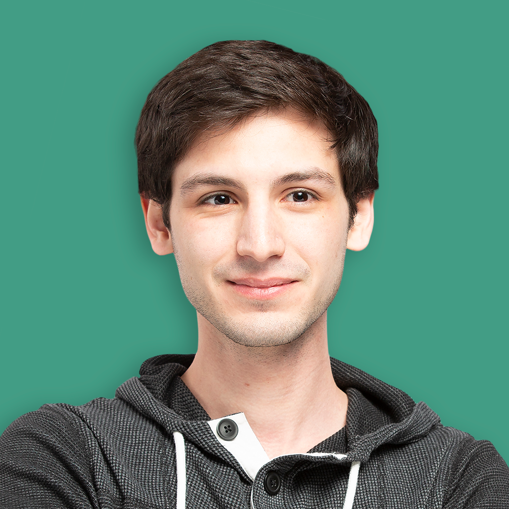 Young man with dark hair and light skin smiling, wearing a black hoodie, against a solid green background.