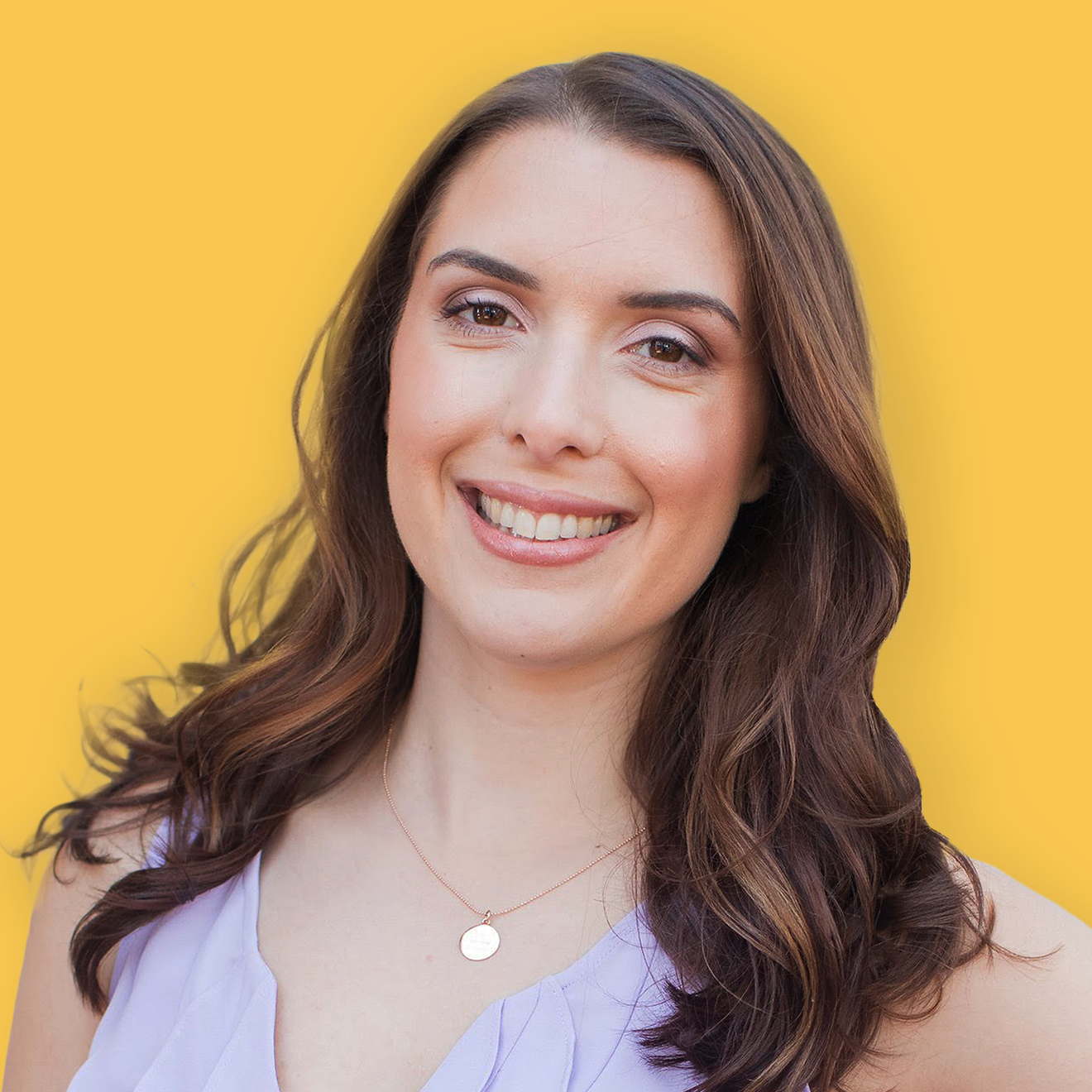 A smiling young woman with long wavy brown hair, wearing a light purple sleeveless top and a gold necklace with a circular pendant, standing against a yellow background.