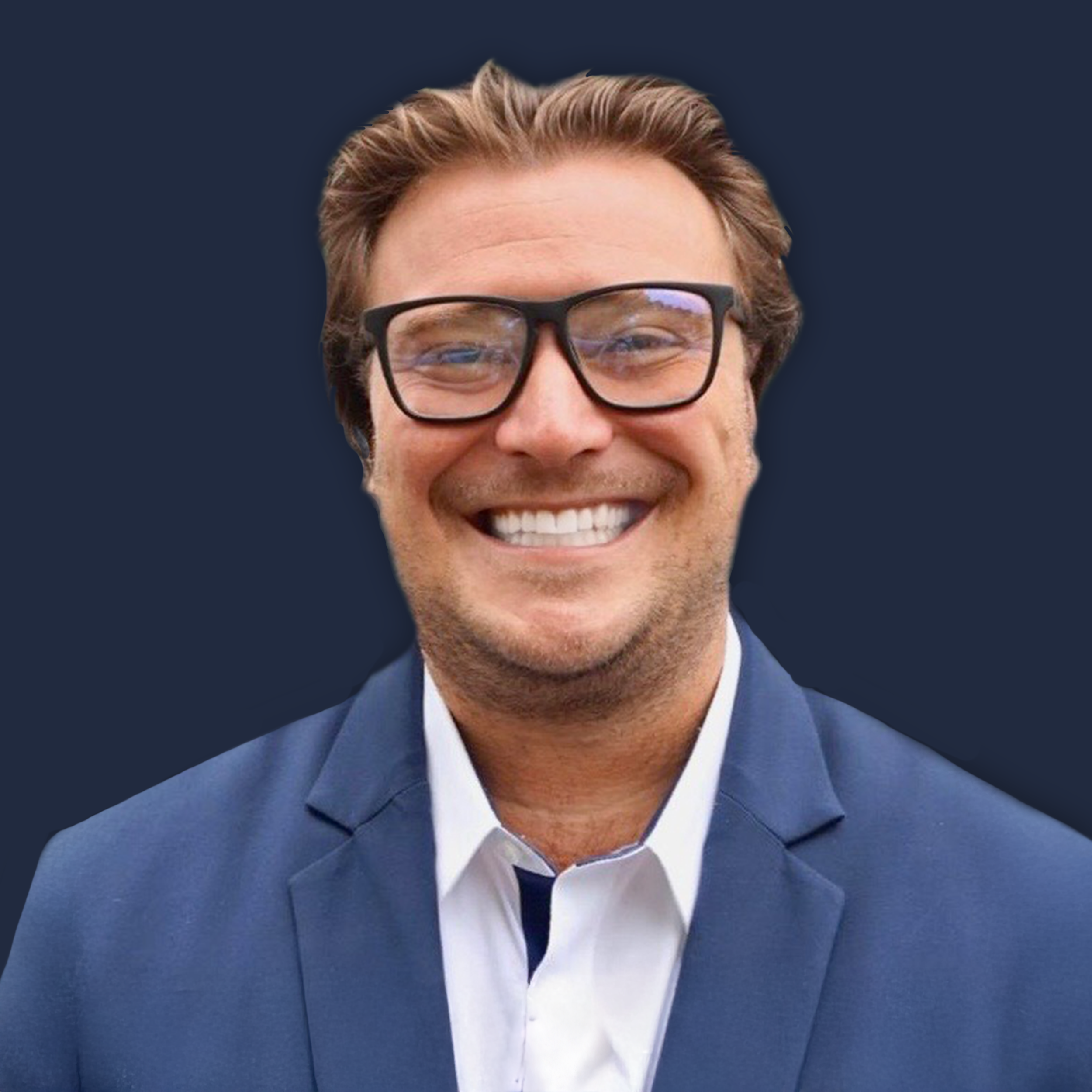 Close-up of a smiling man wearing glasses, a suit, and a tie, with brown hair styled back, against a dark background.