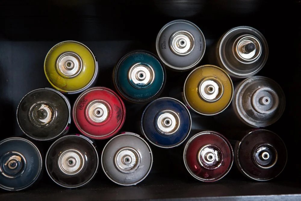 Top view of spray paint cans arranged upright in a black container.
