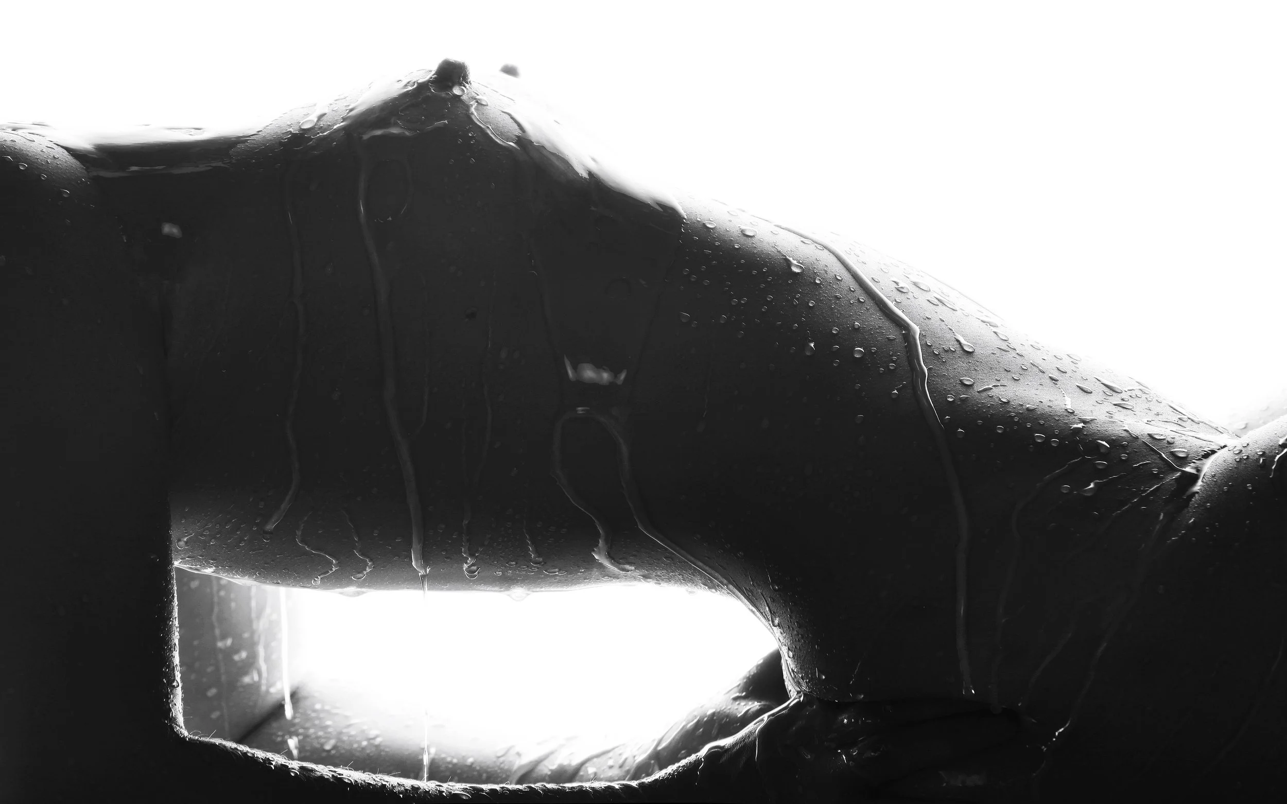 Close-up of a person's arm, with water droplets and rain streaks on the skin, in black and white.