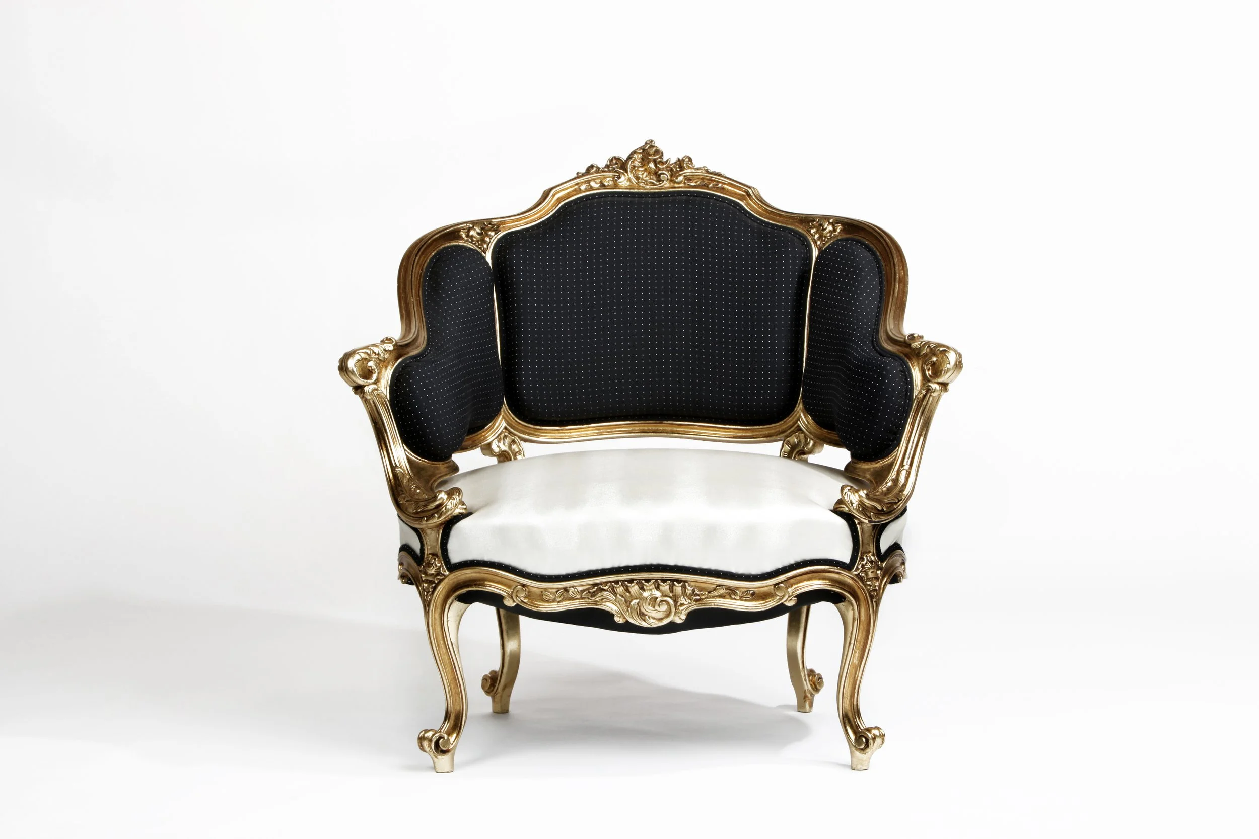 A vintage-style sofa with ornate gold wood carvings and black upholstery with small white polka dots, set against a white background.