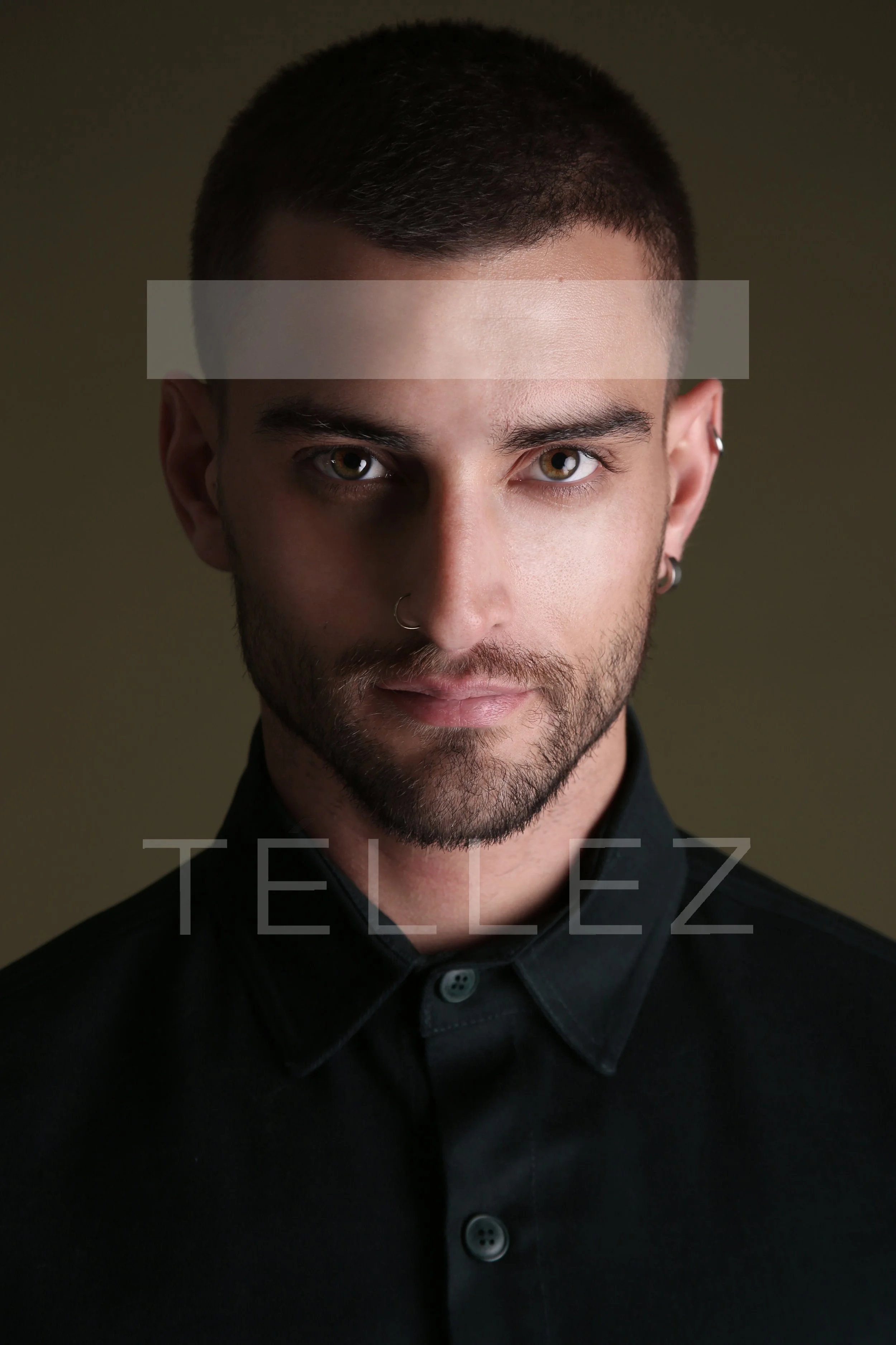 Close-up portrait of a man with short dark hair, light brown eyes, and a beard, wearing a black button-up shirt with a high collar, against a dark background, with the word 'TELLEZ' overlaid.