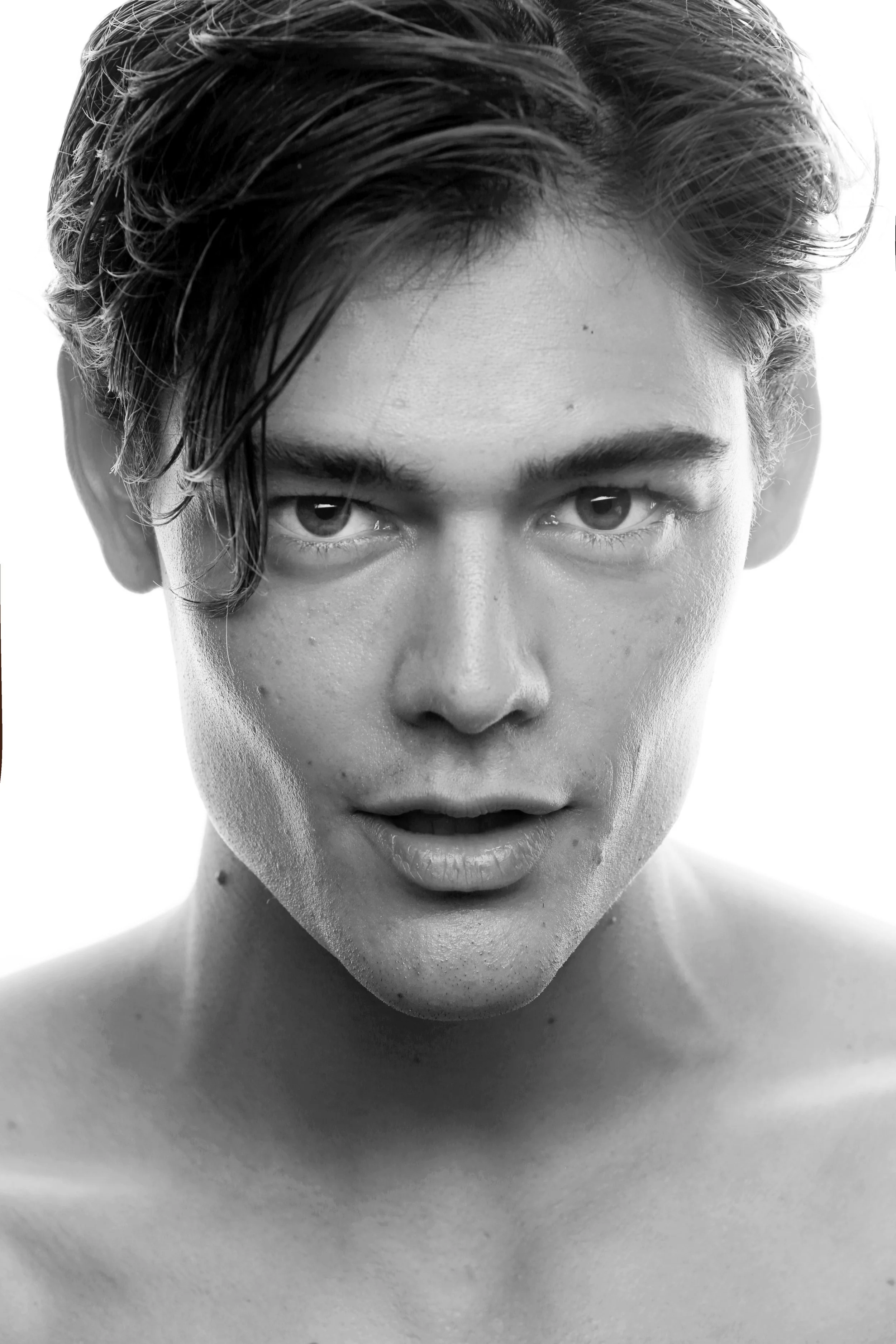 Black and white close-up portrait of a person with wet, tousled hair, open mouth, and no clothing visible, focusing on facial expression and upper body.