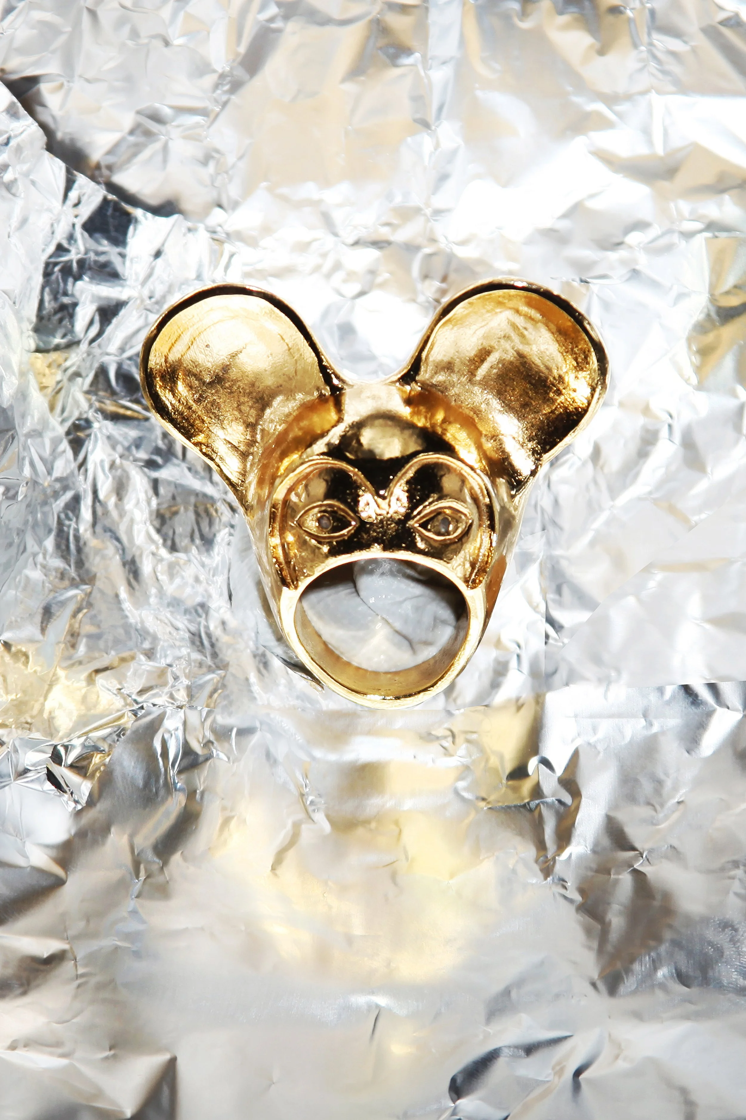 A shiny gold bear-shaped lighter on crinkled aluminum foil.