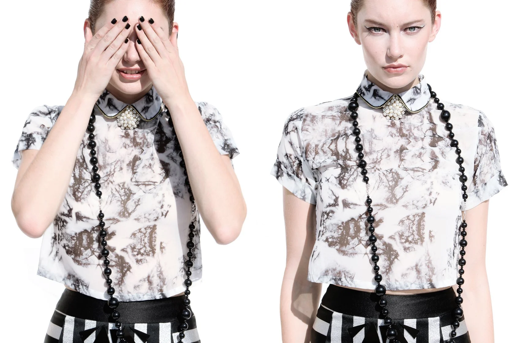 Two women with similar outfits, one covering her eyes and the other looking forward, both wearing patterned shirts, black and white striped shorts, and long black beaded necklaces.