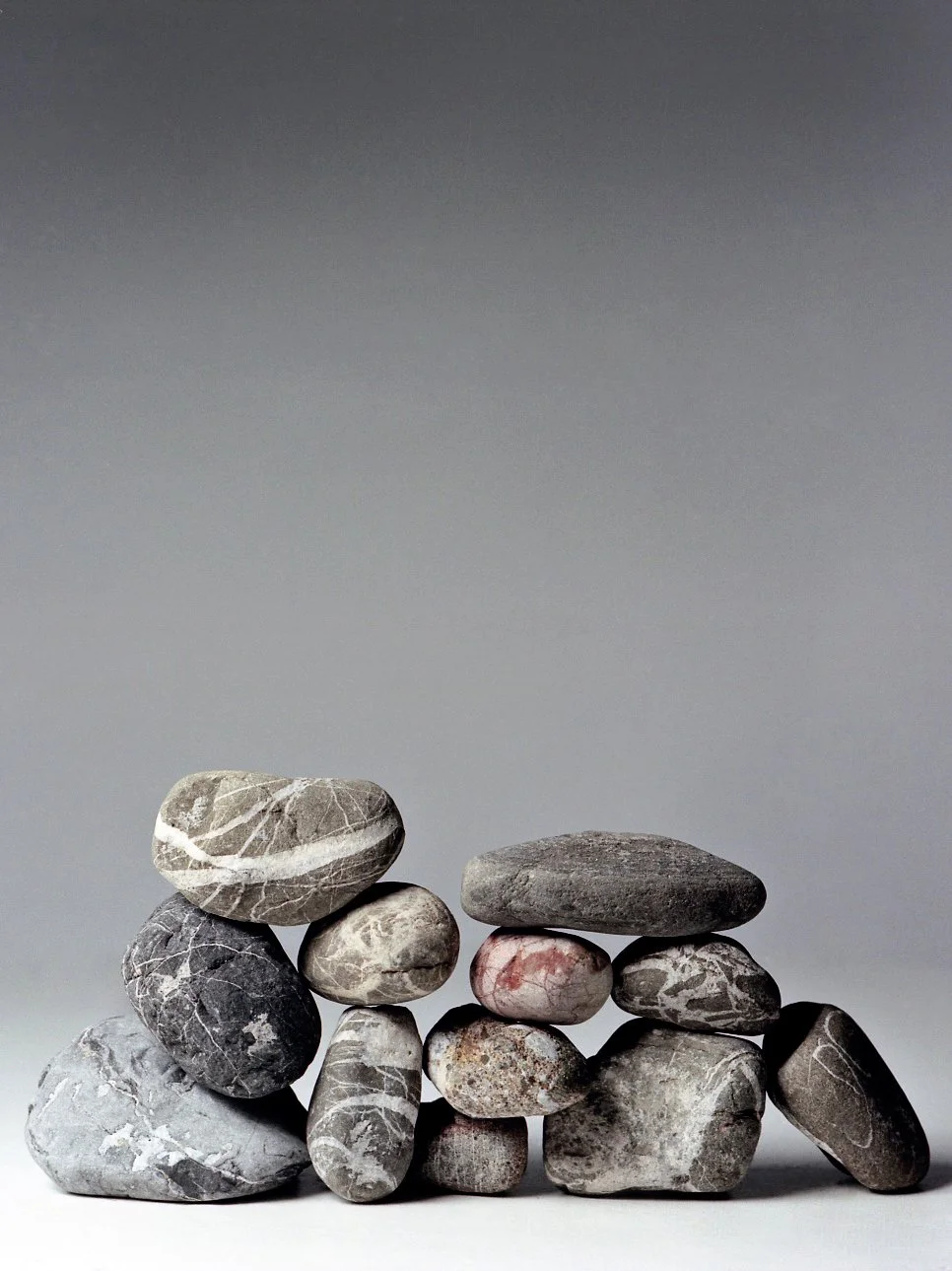 A collection of arranged smooth stones stacked and balanced on a flat surface against a neutral background.