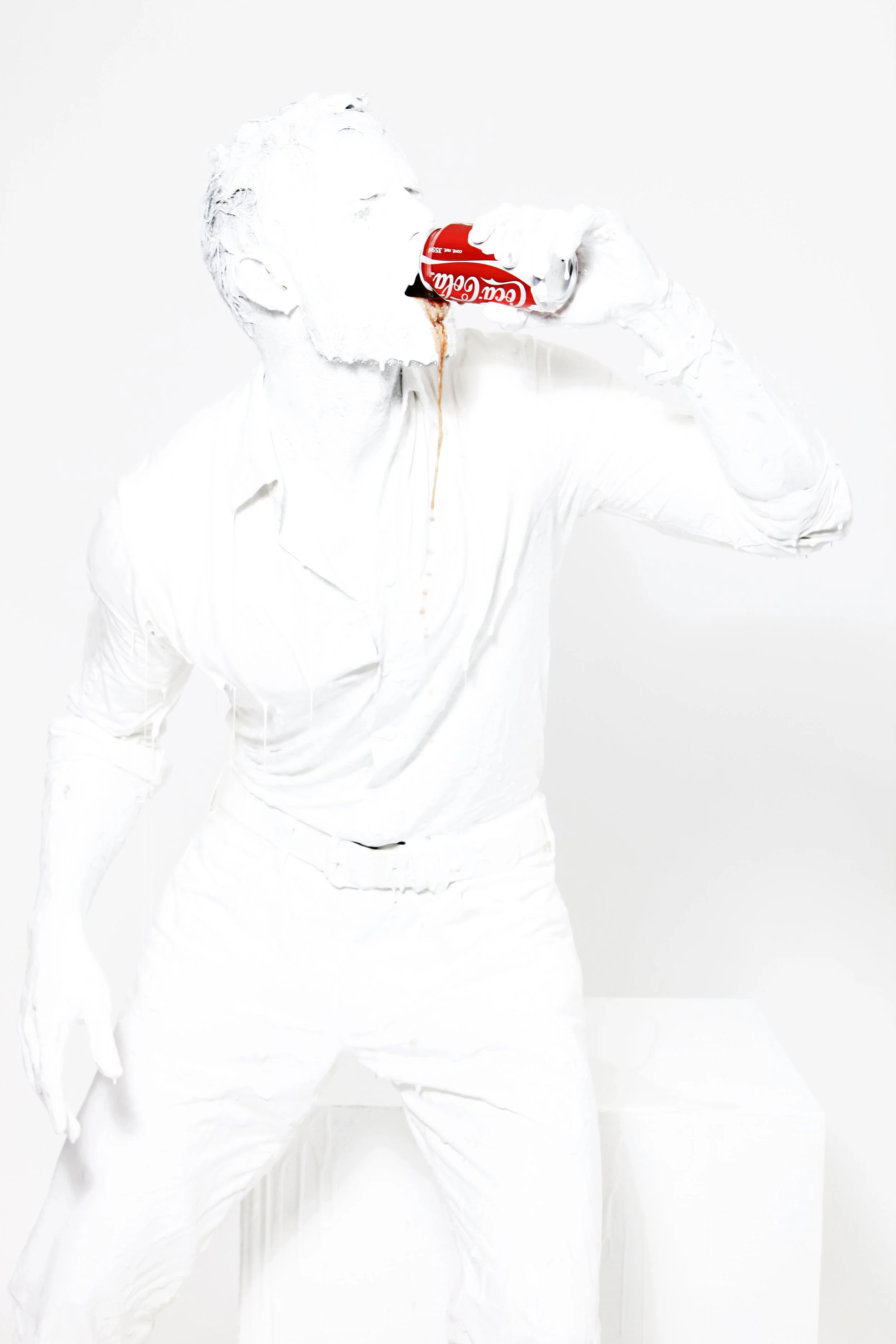 A person in all white clothing and gloves is drinking a can of Coca-Cola against a plain white background.