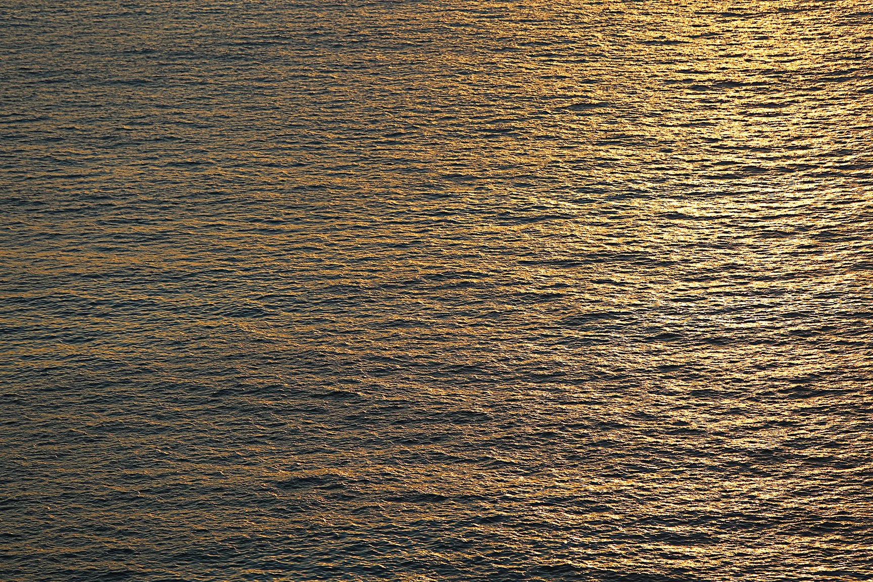 A body of water reflecting the golden light of the setting or rising sun.