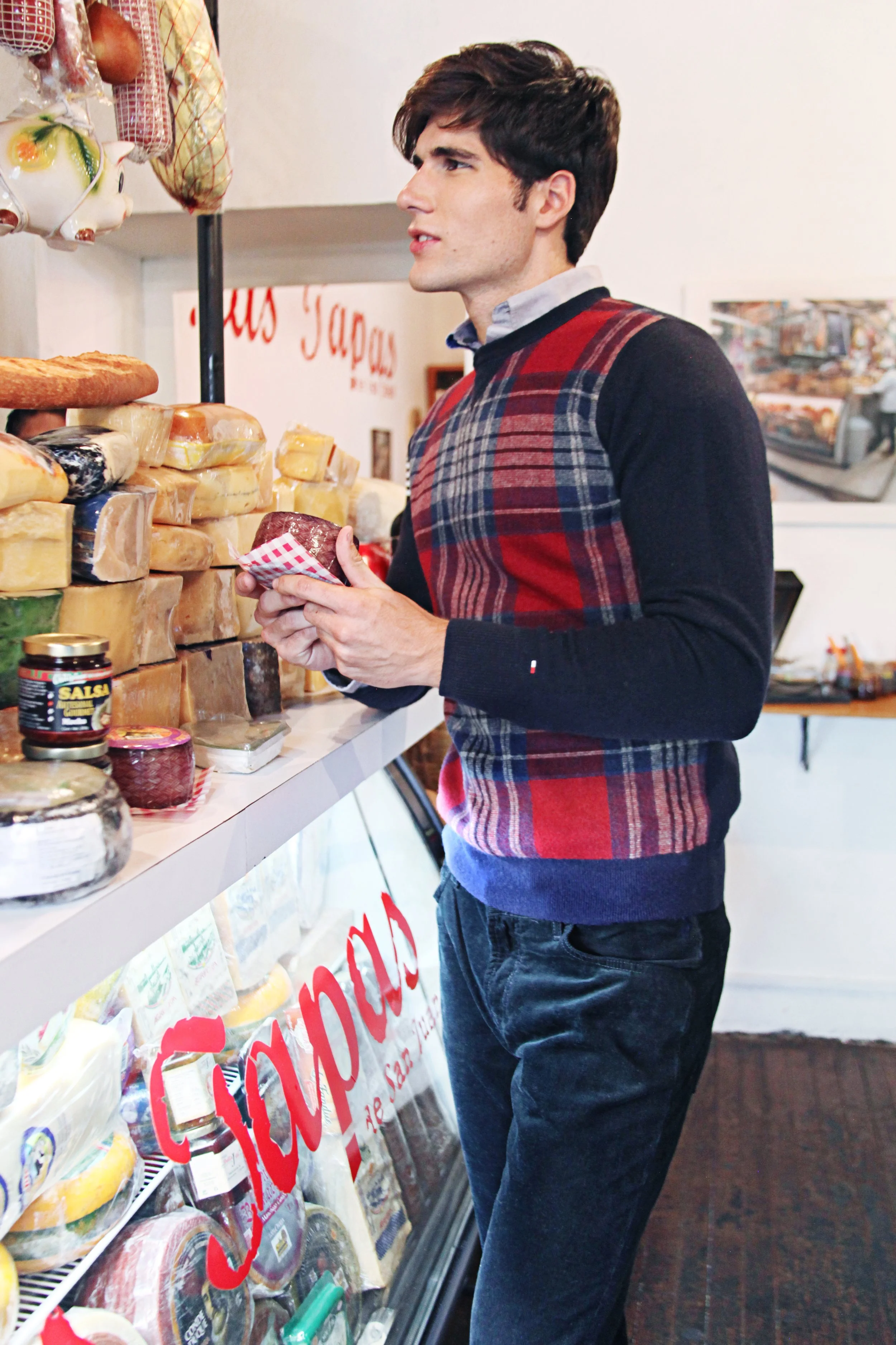 A man shopping for cheese at a grocery store or cheese shop.