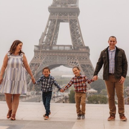 Family of four holding hands in front of the Eiffel Tower in Paris, France.