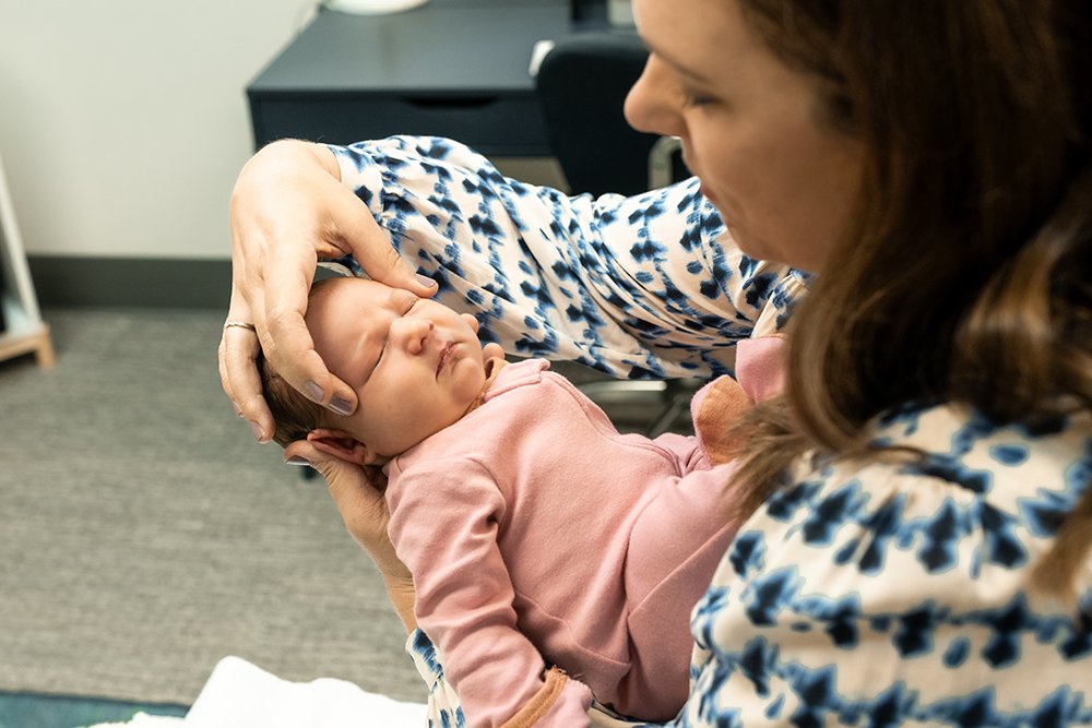 Dr. Shannon performs craniosacral thearpy on a baby wearing a pink onsie who is relaxed and calm Camas Wa
