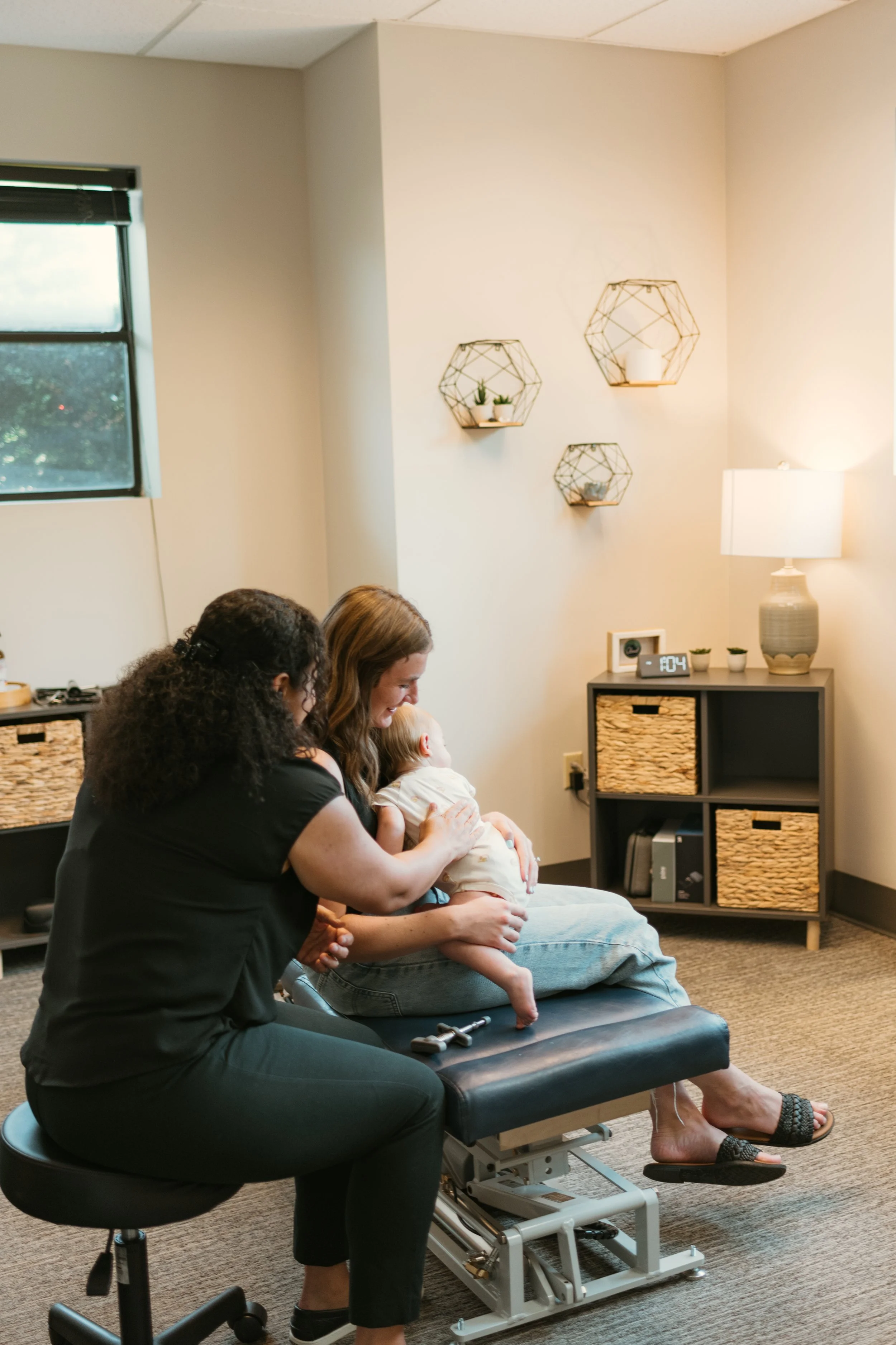Dr. Ashley preforming chiropractic adjustment on a child while the mom is holdin her Camas wa