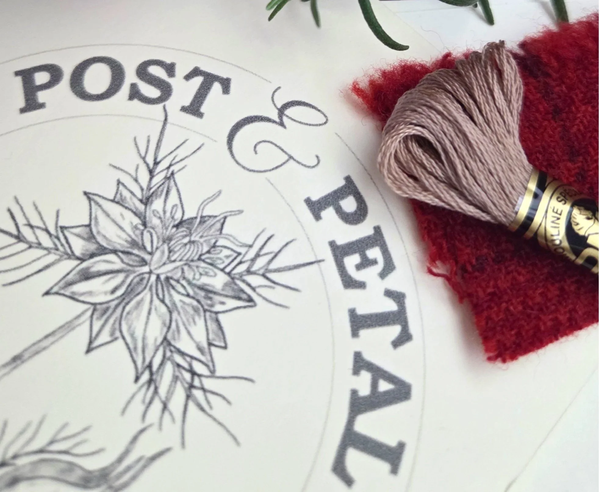 Post & Petal branding and logo design. A lifestyle shot of botanical art, embroidery thread, and fresh rosemary, illustrating the intersection of storytelling, hand-work, and quiet curiosities.
