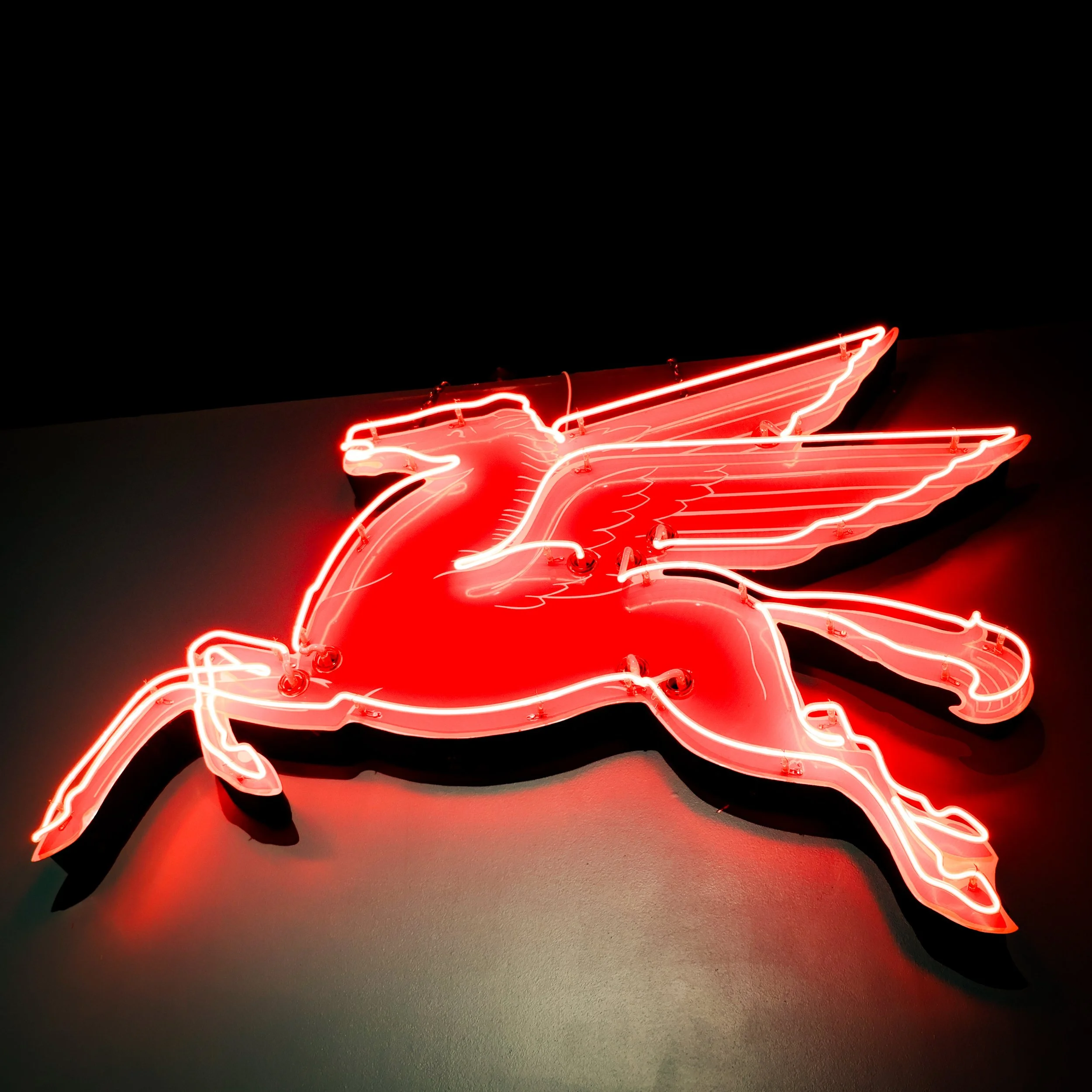 Neon sign of a red fairy or angel with wings, wings, hair, and a long dress.