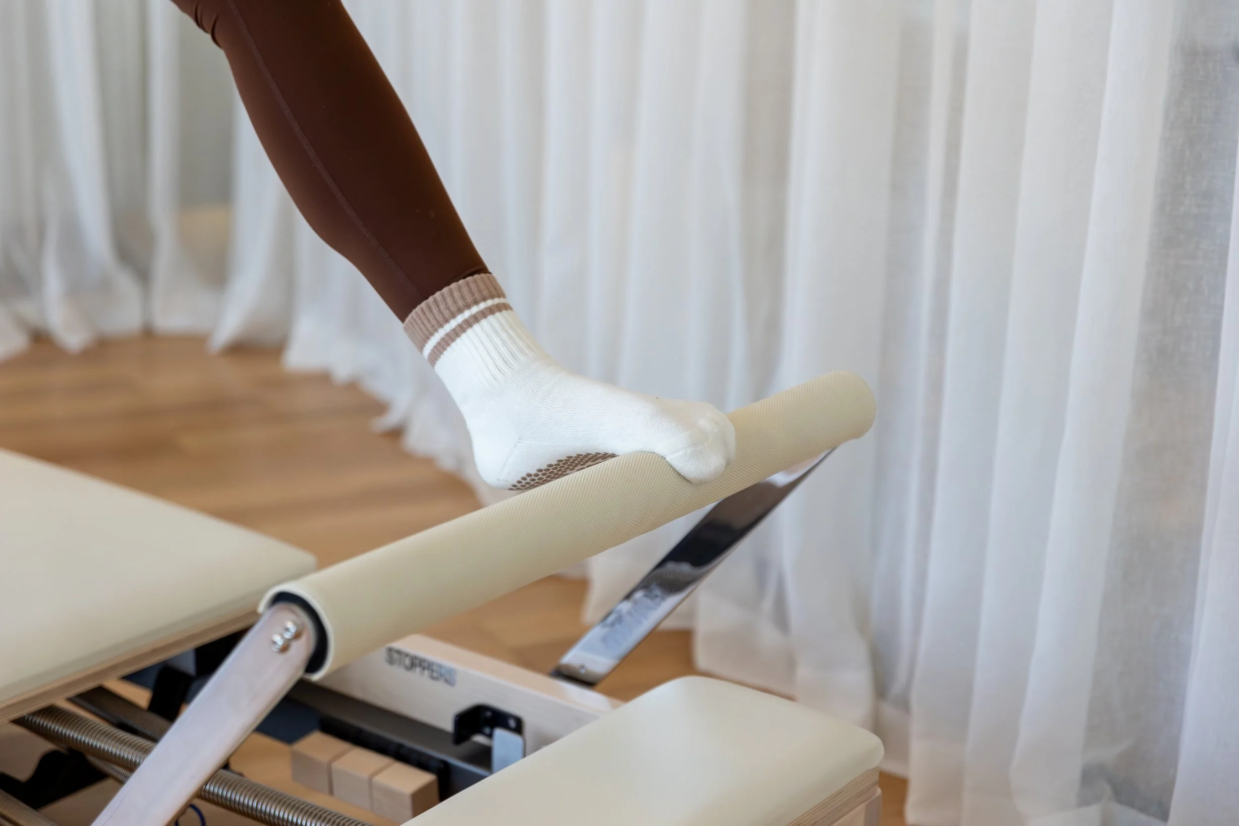 Close-up of a person adjusting a medical or rehabilitation treatment table, with white, brown, and beige parts.