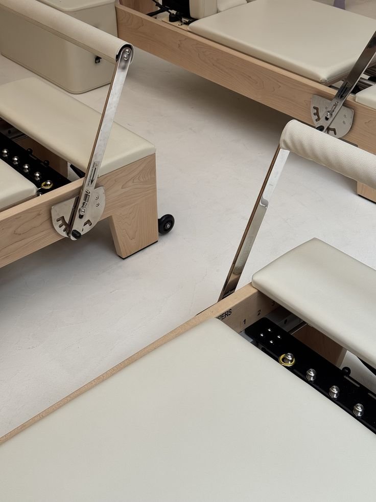 Hospital or medical examination room with wooden beds, white padded chairs, and adjustable metal bed side rails.