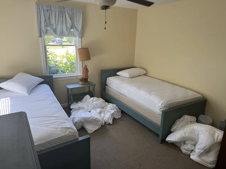 Before: twin bedroom with stripped beds and used linens