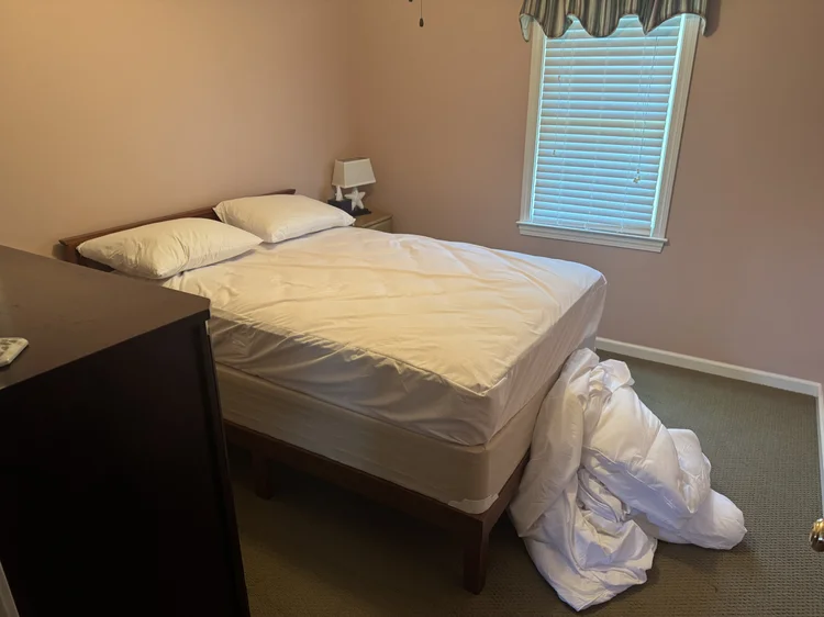 Before: primary bedroom with bed stripped after guests