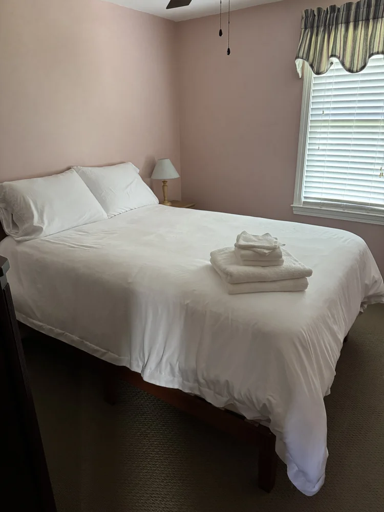 After: primary bedroom made with fresh linens and folded towels