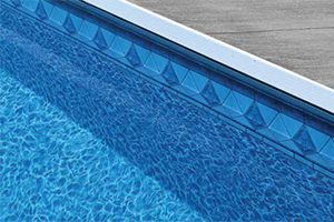 Close-up of the edge of a blue swimming pool with a concrete deck.
