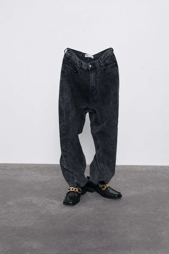 Calça jeans preta longa com sapatos de salto preto com detalhe dourado