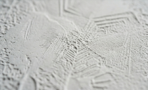 Close-up of textured white plaster wall with decorative patterns