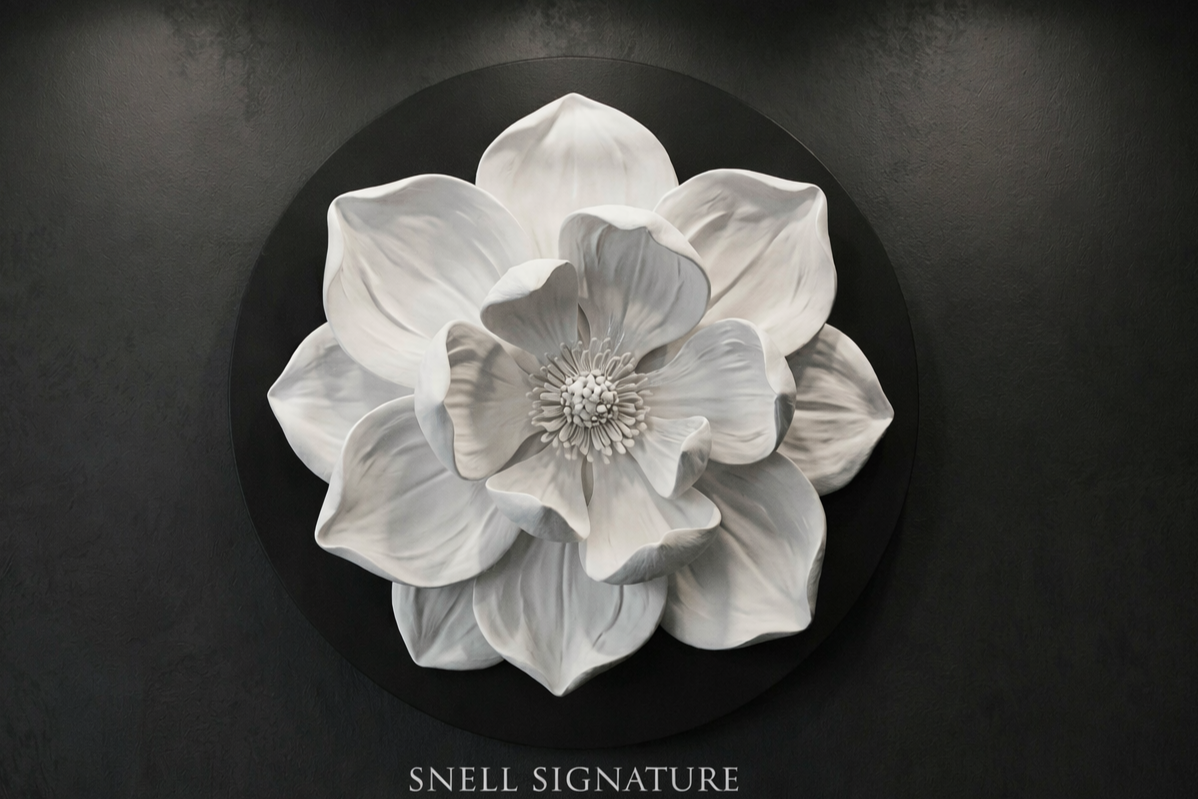 A monochromatic, detailed 3D sculpture of a large flower with multiple petals mounted on a dark wall, with the words 'SNELL SIGNATURE' underneath.