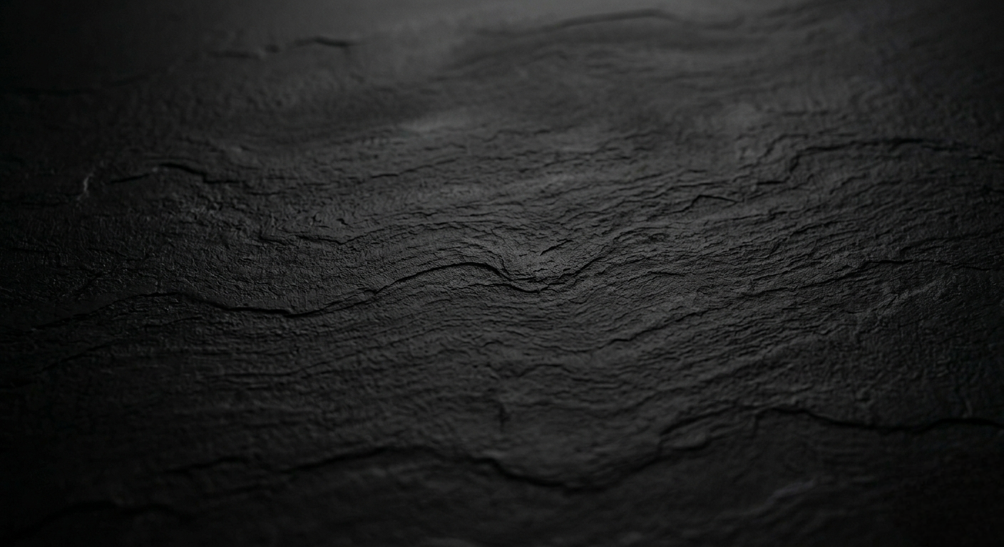 Close-up of a black, textured, slightly glossy surface with visible cracks and ridges.