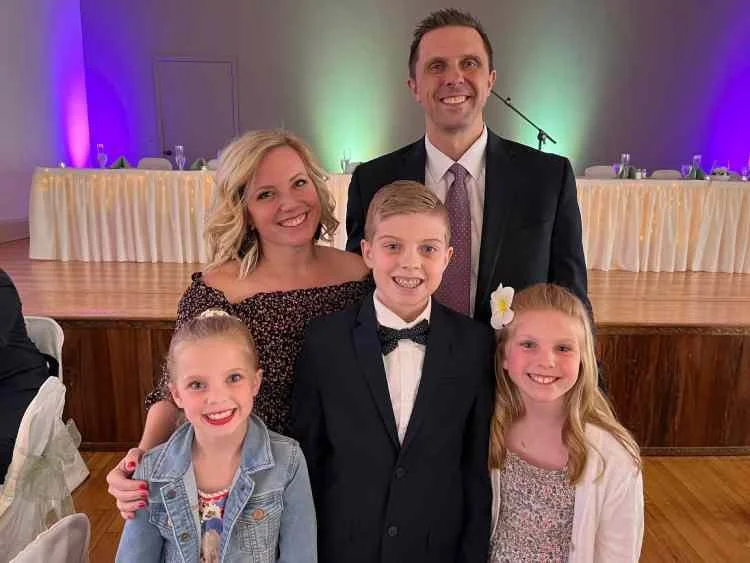 A family of five at a celebration, group portrait with a decorated venue and stage in the background
