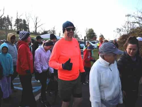 A group of people gathered outdoors, some in athletic clothing, suggesting they are participating in or preparing for a walk or run event.