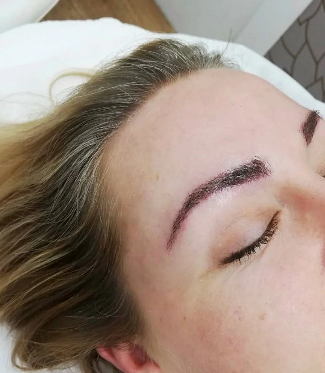 Close-up of a woman's face showing freshly microbladed eyebrows.