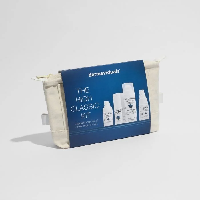 A beige travel toiletry bag with a blue product kit label attached, displaying skincare products from dermaviduals, labeled 'The High Classic Kit'.