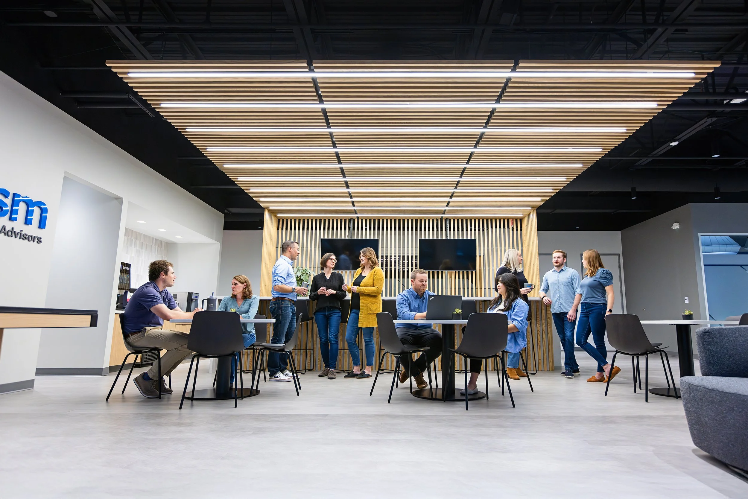 Employees working and chatting in a bright open office lounge, KSM brand photography in Indianapolis