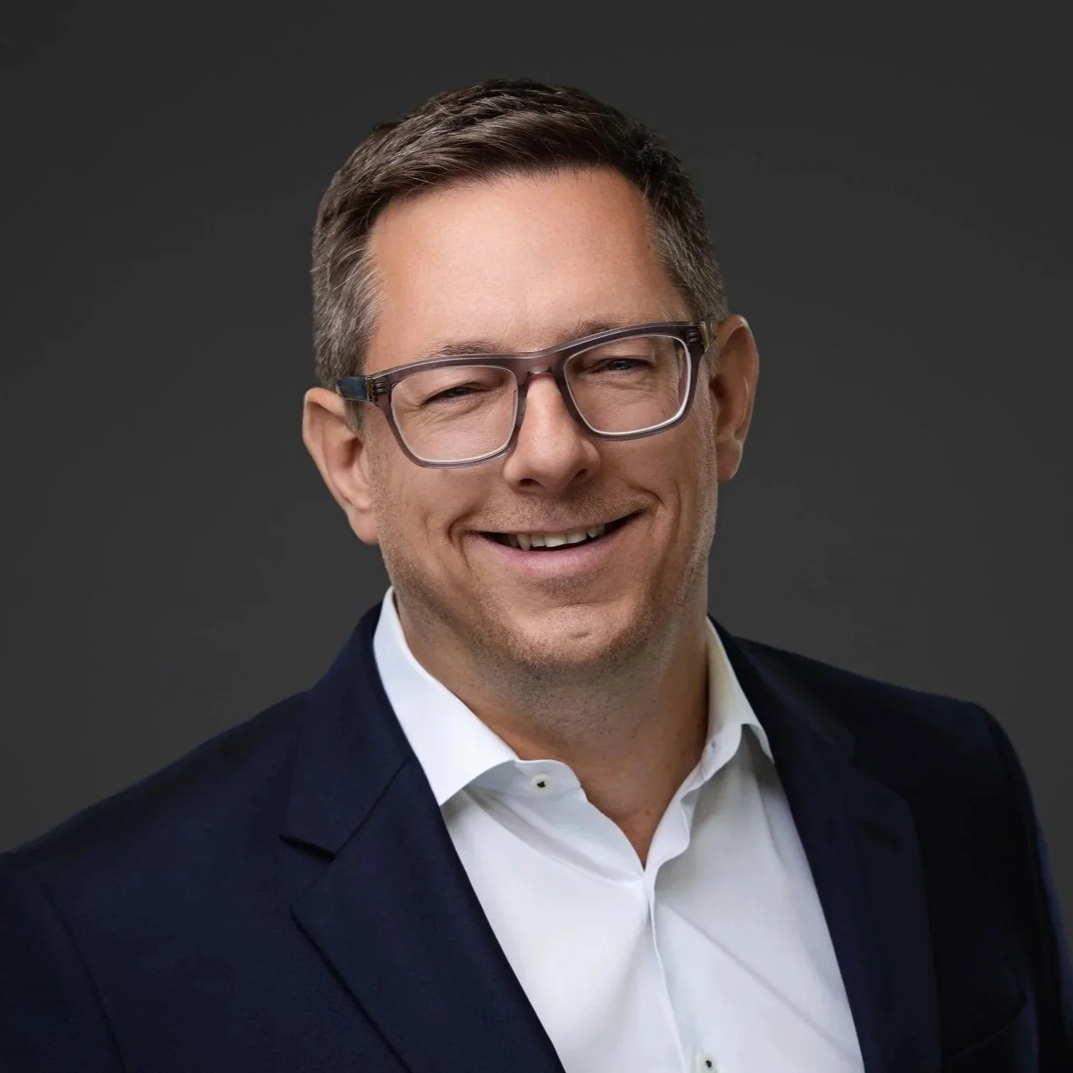 Smiling man in glasses and a navy suit, professional business headshot in Fishers