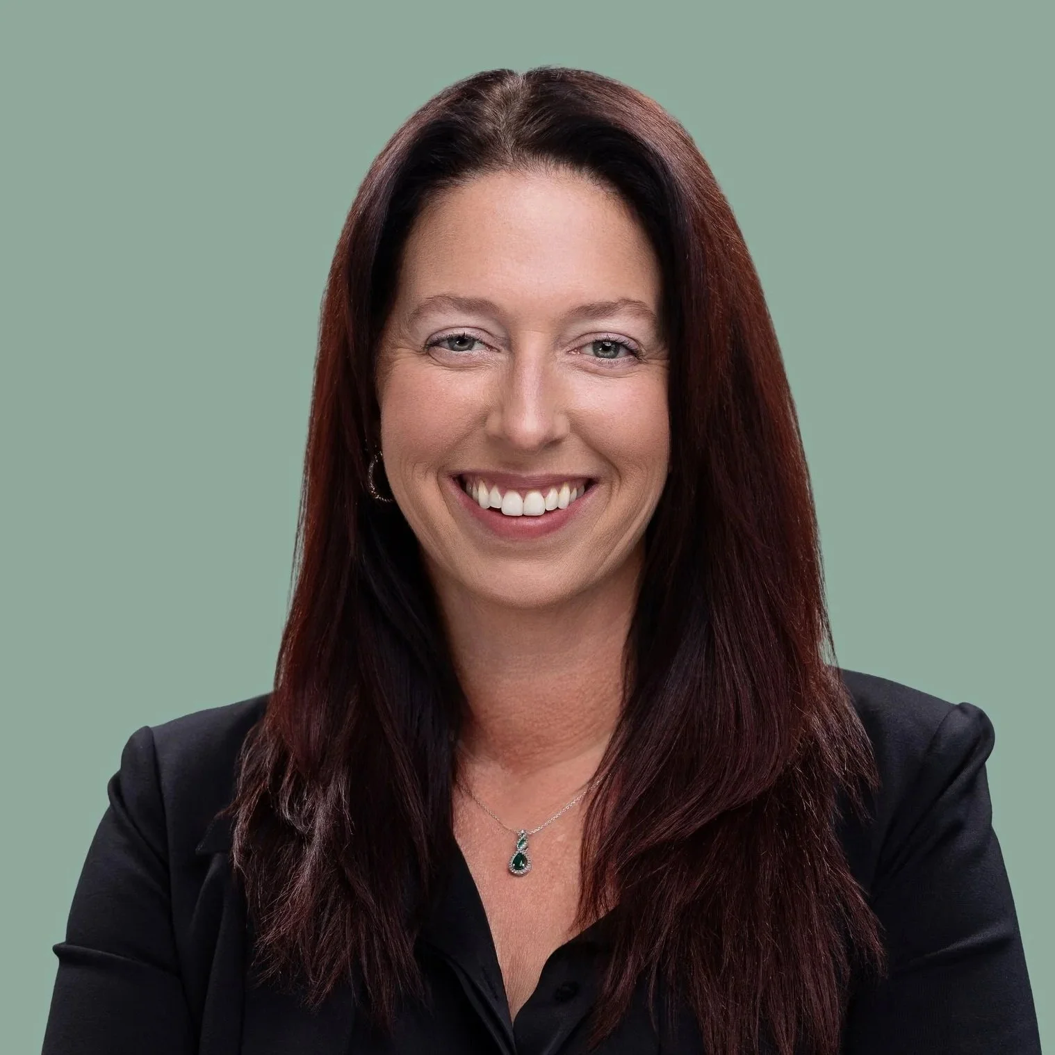 Smiling woman with long auburn hair in a black blazer, professional headshot in Fishers