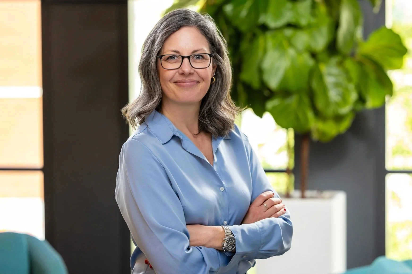 Smiling woman in glasses and a blue shirt with arms crossed, Cummins employee portrait