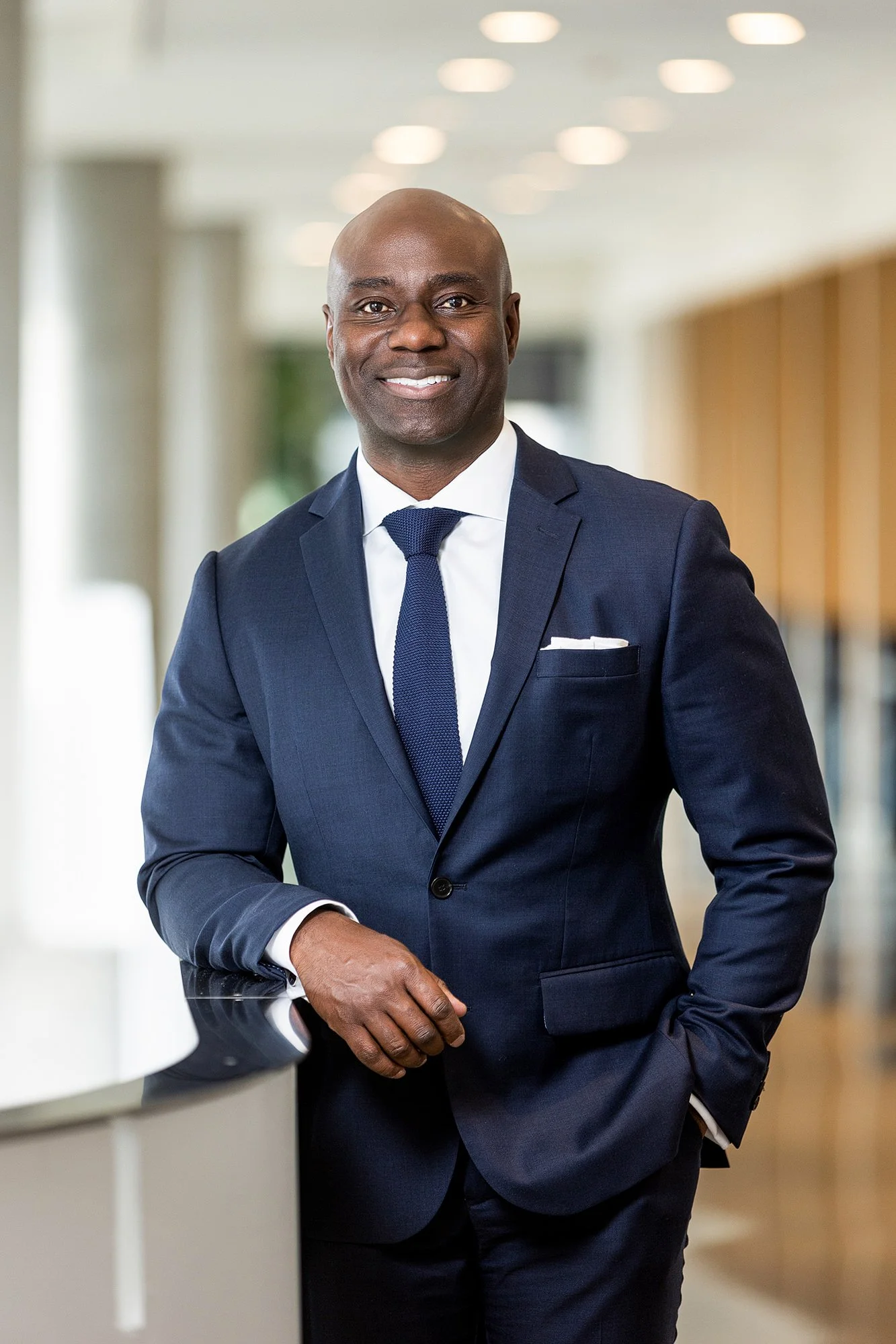 Executive in a navy suit standing with arms crossed in a modern office, Cummins corporate portrait