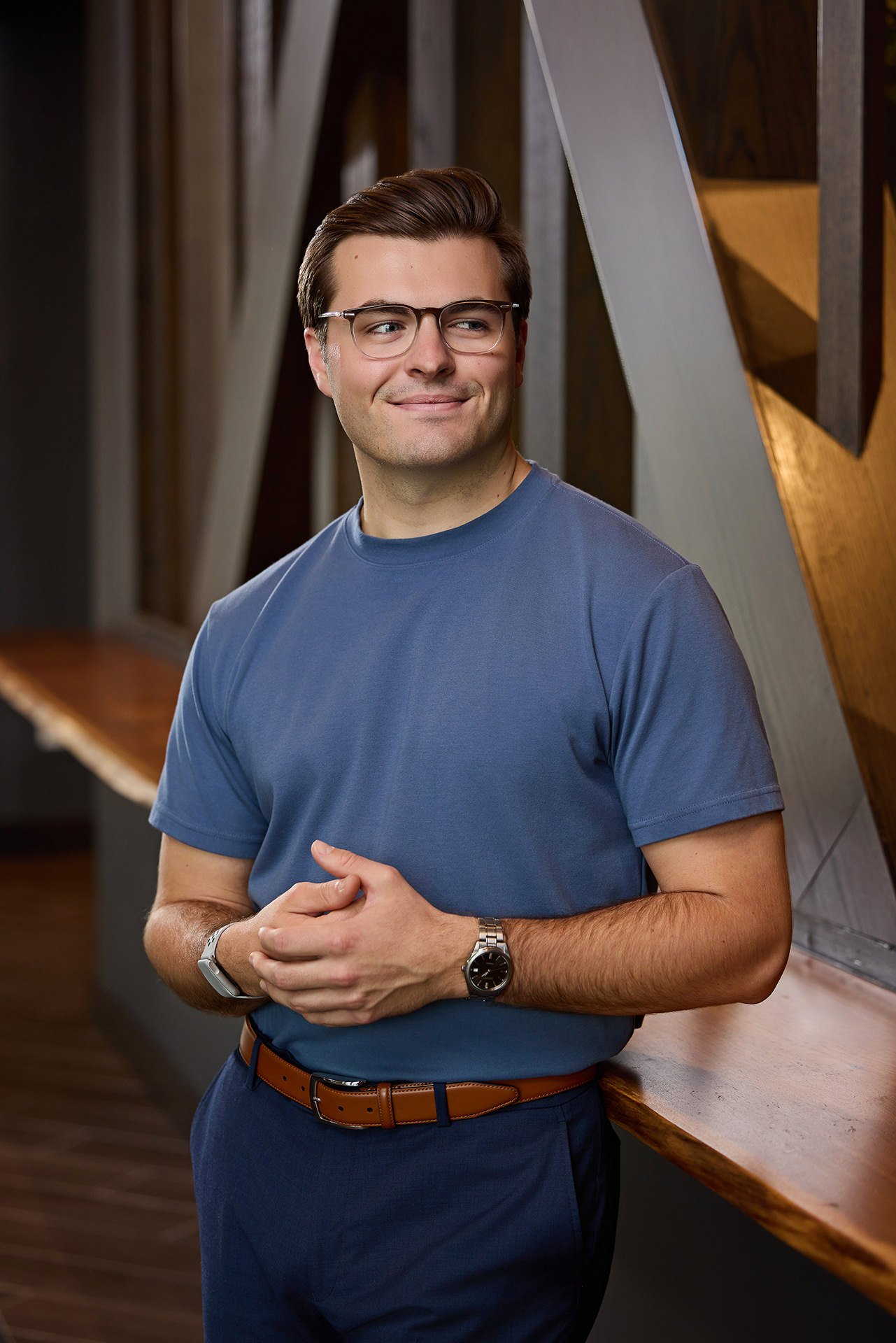 Smiling man in glasses and a blue T-shirt in a modern interior, casual branding portrait by Square Mouth Studios