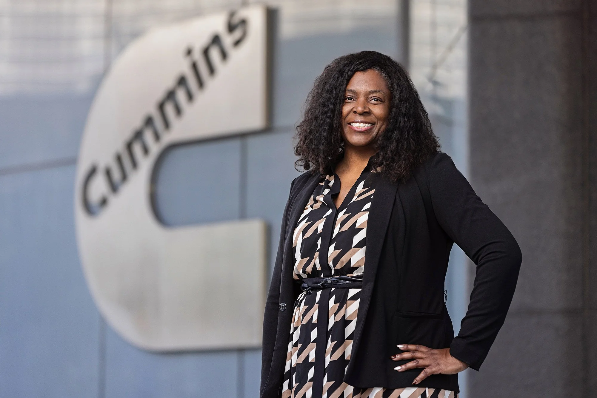 Cummins employee standing in front of the Cummins logo, corporate portrait in Indianapolis