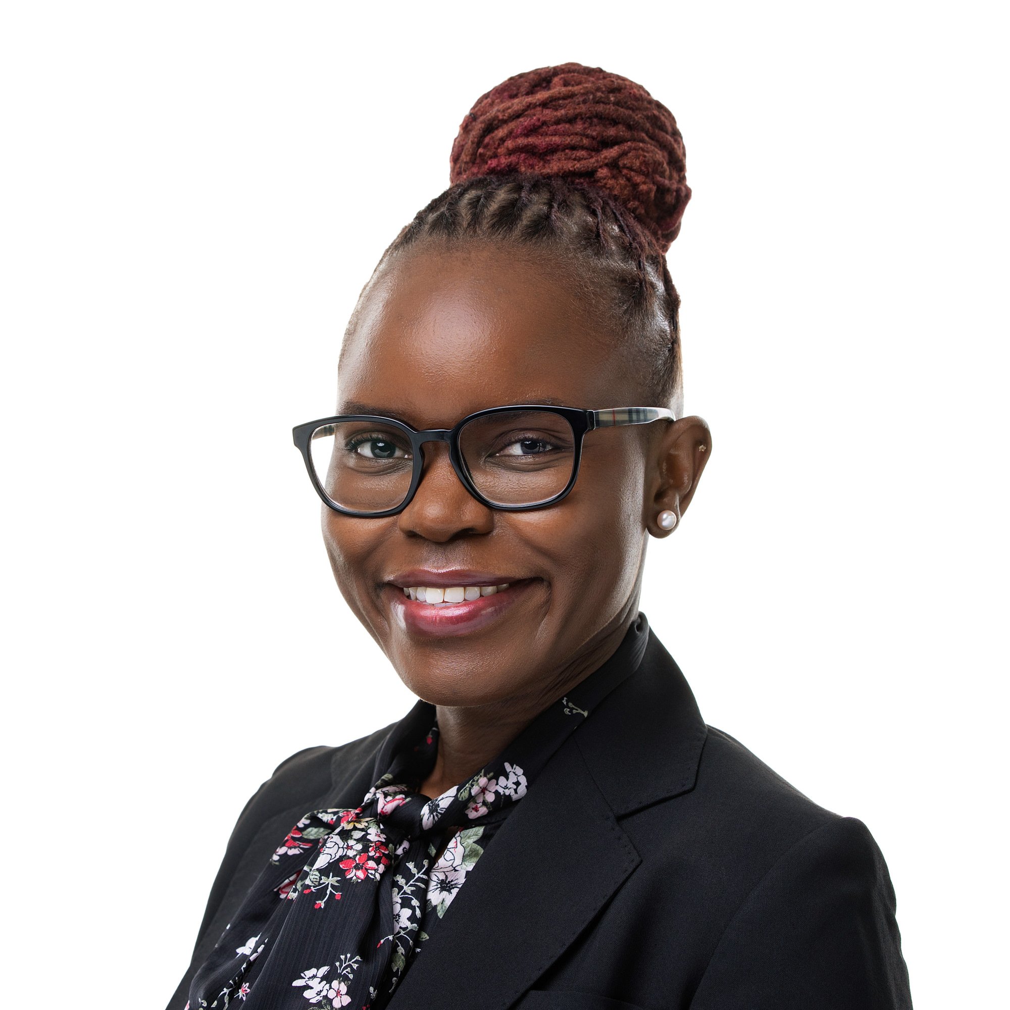 Smiling woman in glasses and a black blazer, professional headshot against a white backdrop