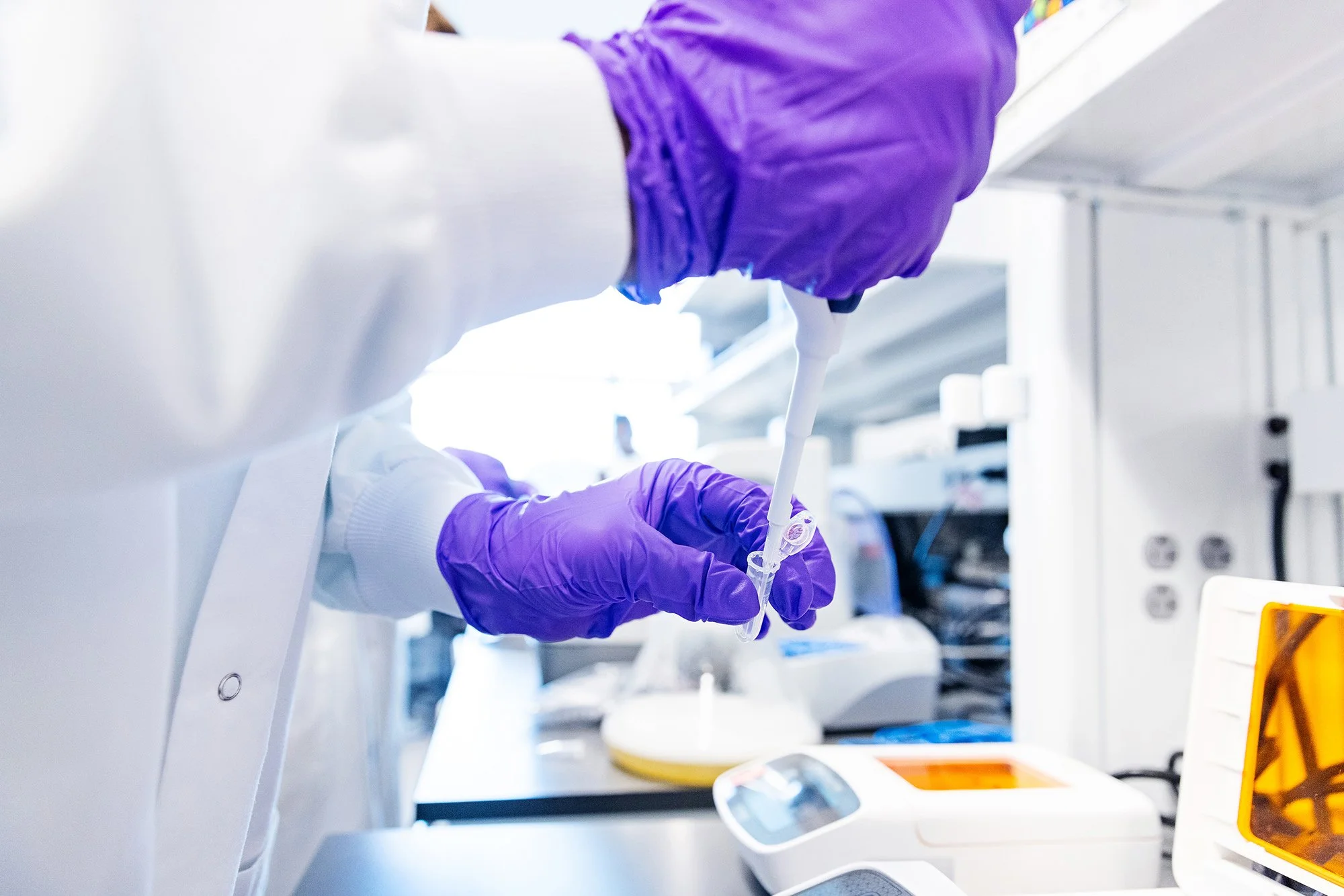 Gloved scientist pipetting samples at a lab bench, BiomEdit brand photography in Indiana
