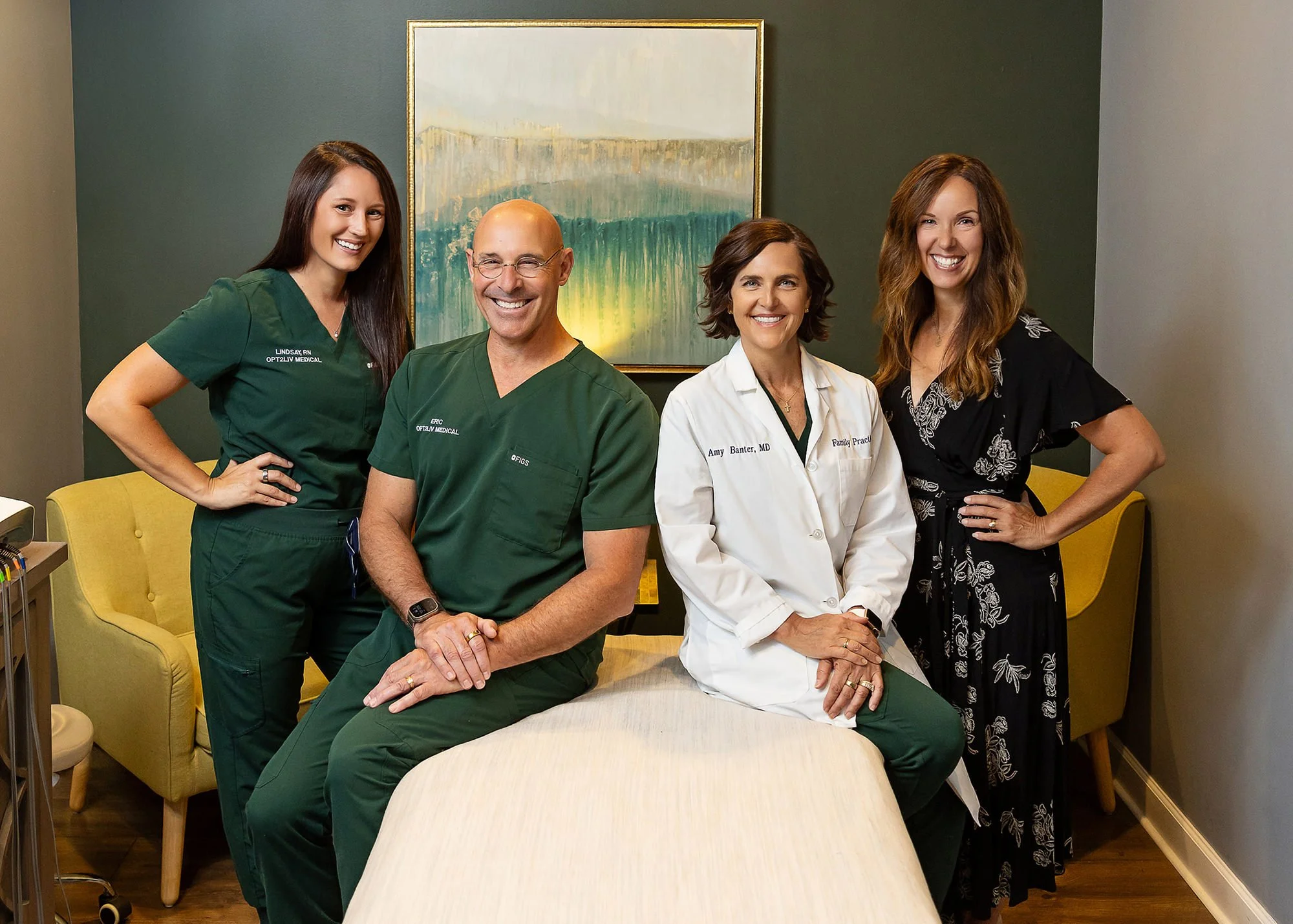 Medical practice team in scrubs and a white coat posing in their treatment room, Central Indiana team photo