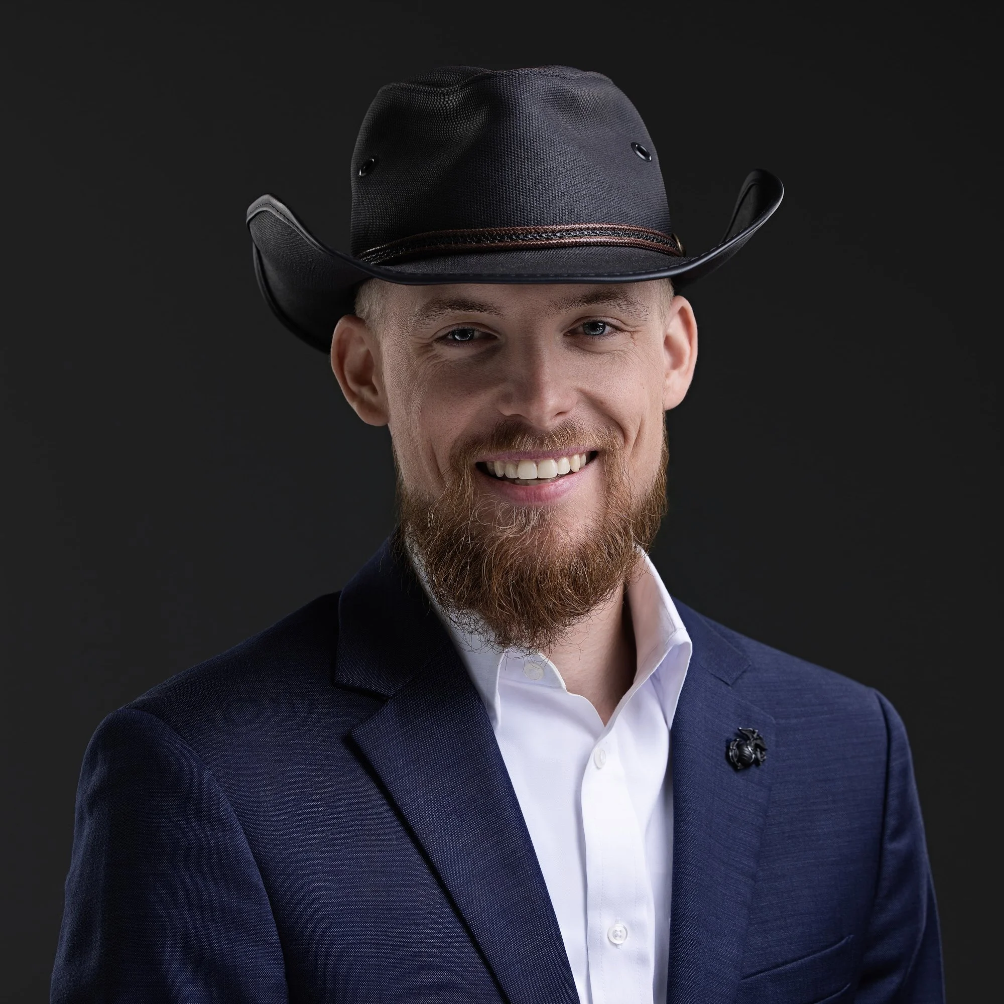Bearded man in a black cowboy hat and navy blazer, personality-driven business headshot